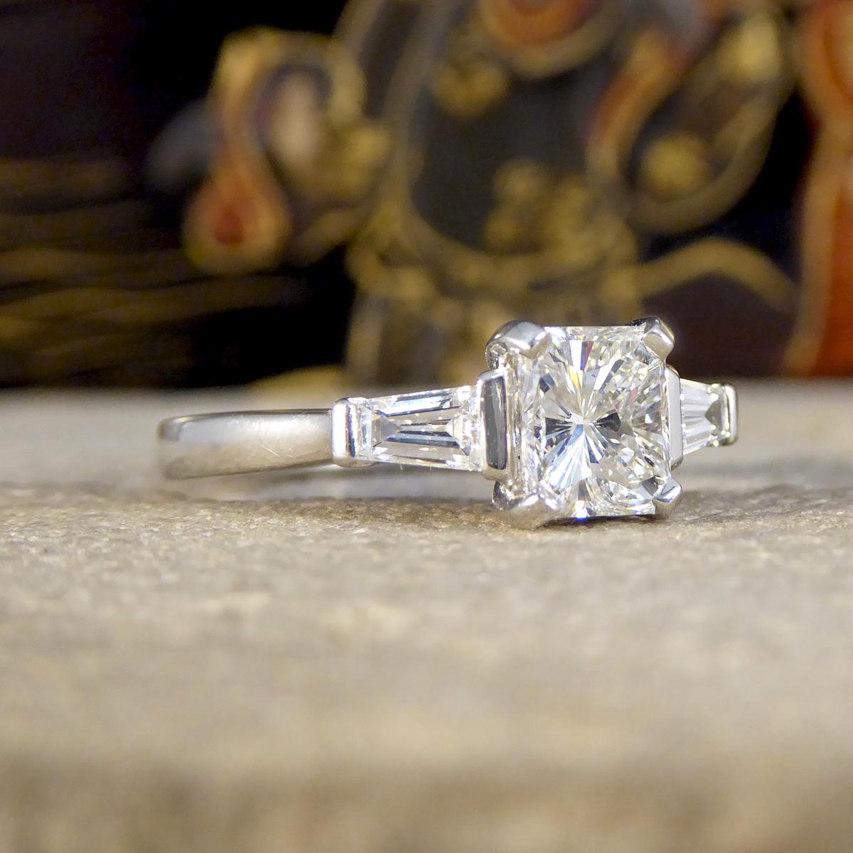 This gorgeous Radiant Cut Diamond ring, set in the finest platinum, is the epitome of elegance and sophistication. At its core sits a breathtaking 1.02ct radiant cut diamond, known for its ability to capture and reflect light, creating a dazzling