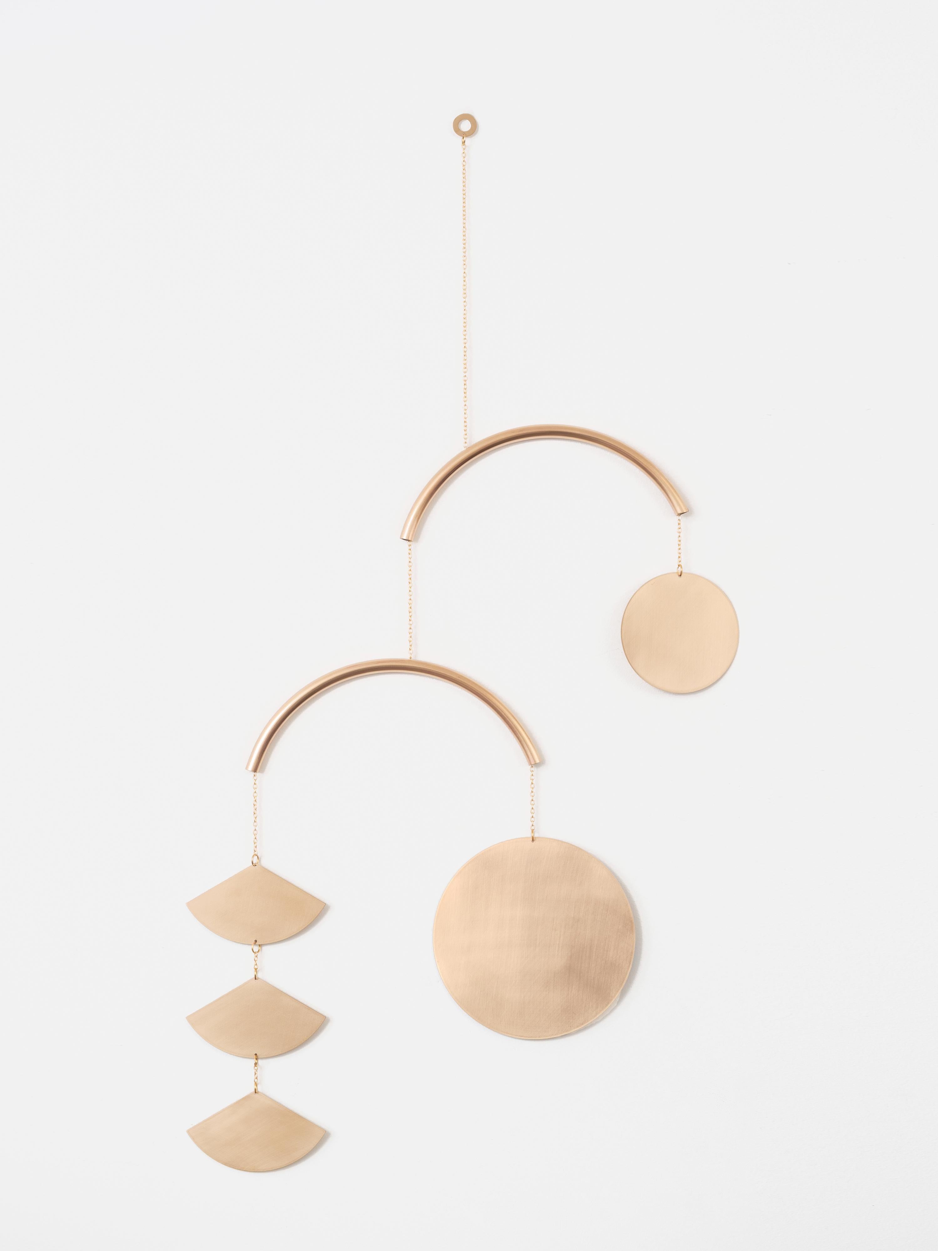The Radiant Mobile explores the division of a circle, gracefully balancing suspended shapes. The curved bar creates fluidity in this captivating piece while the blush tones of the polished bronze radiate warmth within this kinetic mobile.