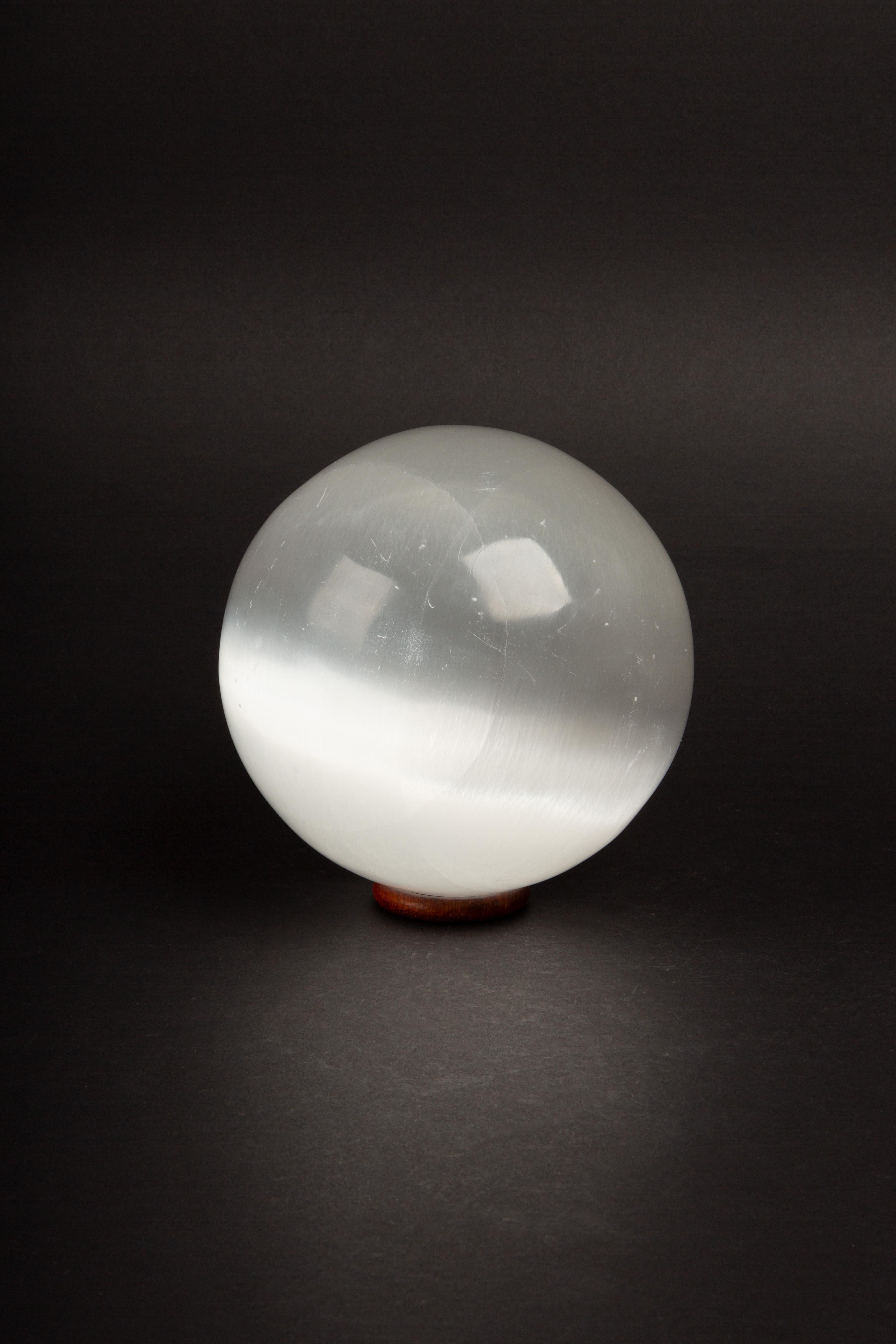 Questa straordinaria sfera di selenite di 6 pollici è una testimonianza dell'abilità artigianale e della bellezza naturale delle montagne dell'Atlante in Marocco, dove è stata accuratamente estratta, scolpita e lucidata. Grazie alla sua morbida e