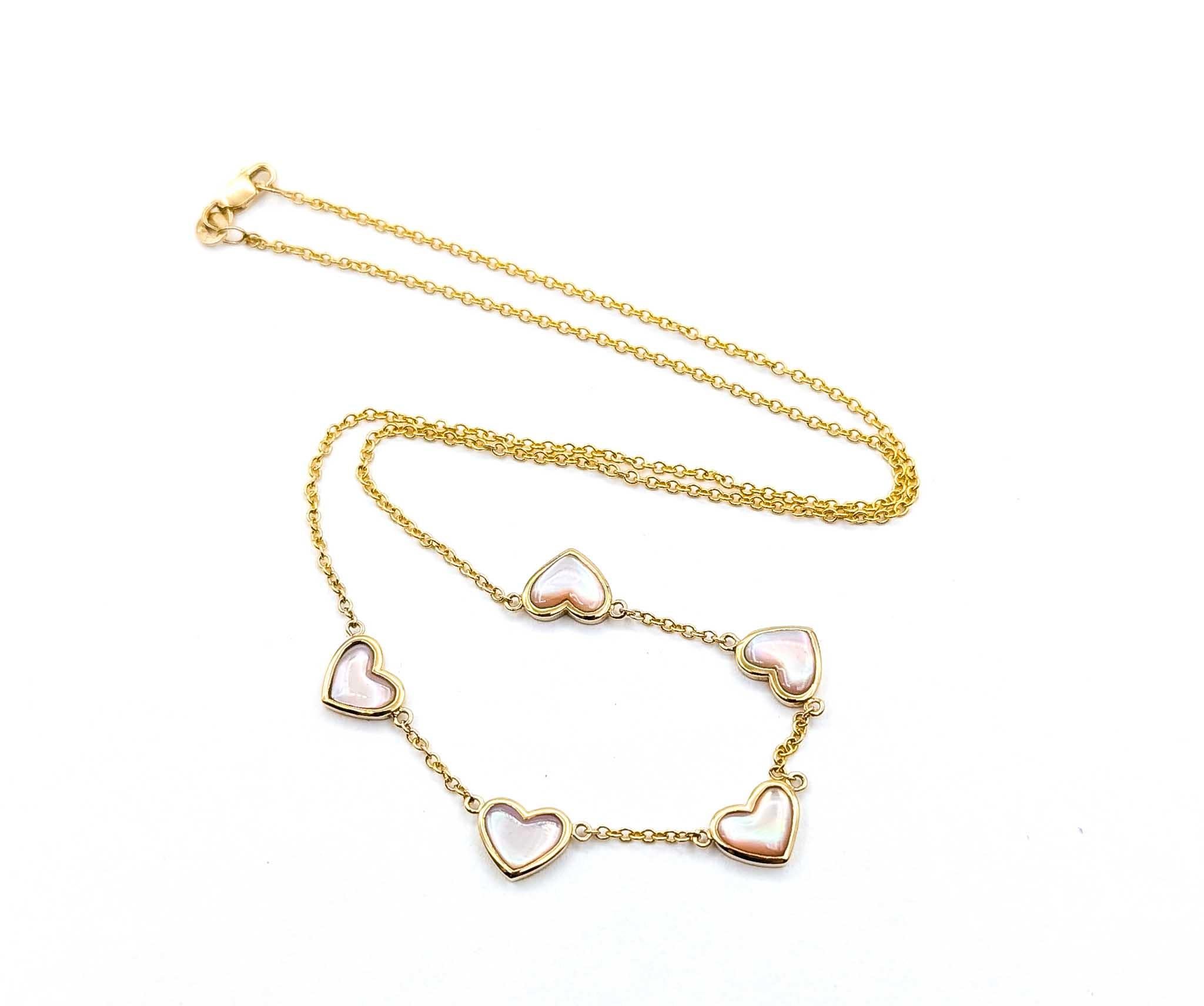 This charming necklace features five luminous mother of pearl hearts, each measuring approximately 8mm, set in warm 14k yellow gold bezels. The soft iridescence of the 2.00 carat total weight of mother of pearl adds a romantic glow, beautifully