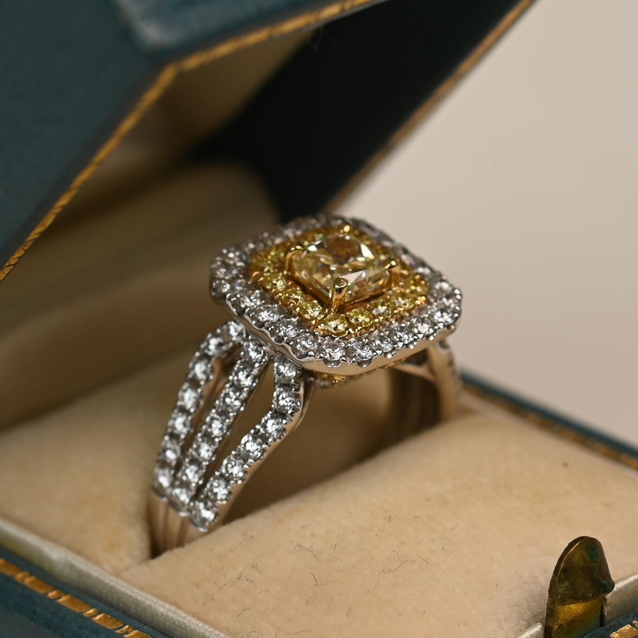 This striking ring showcases a radiant cut yellow diamond at its center, graded VS1 in clarity. Surrounding the center stone is a luminous double halo of yellow and white diamonds, enhancing its brilliance and creating a bold yet elegant