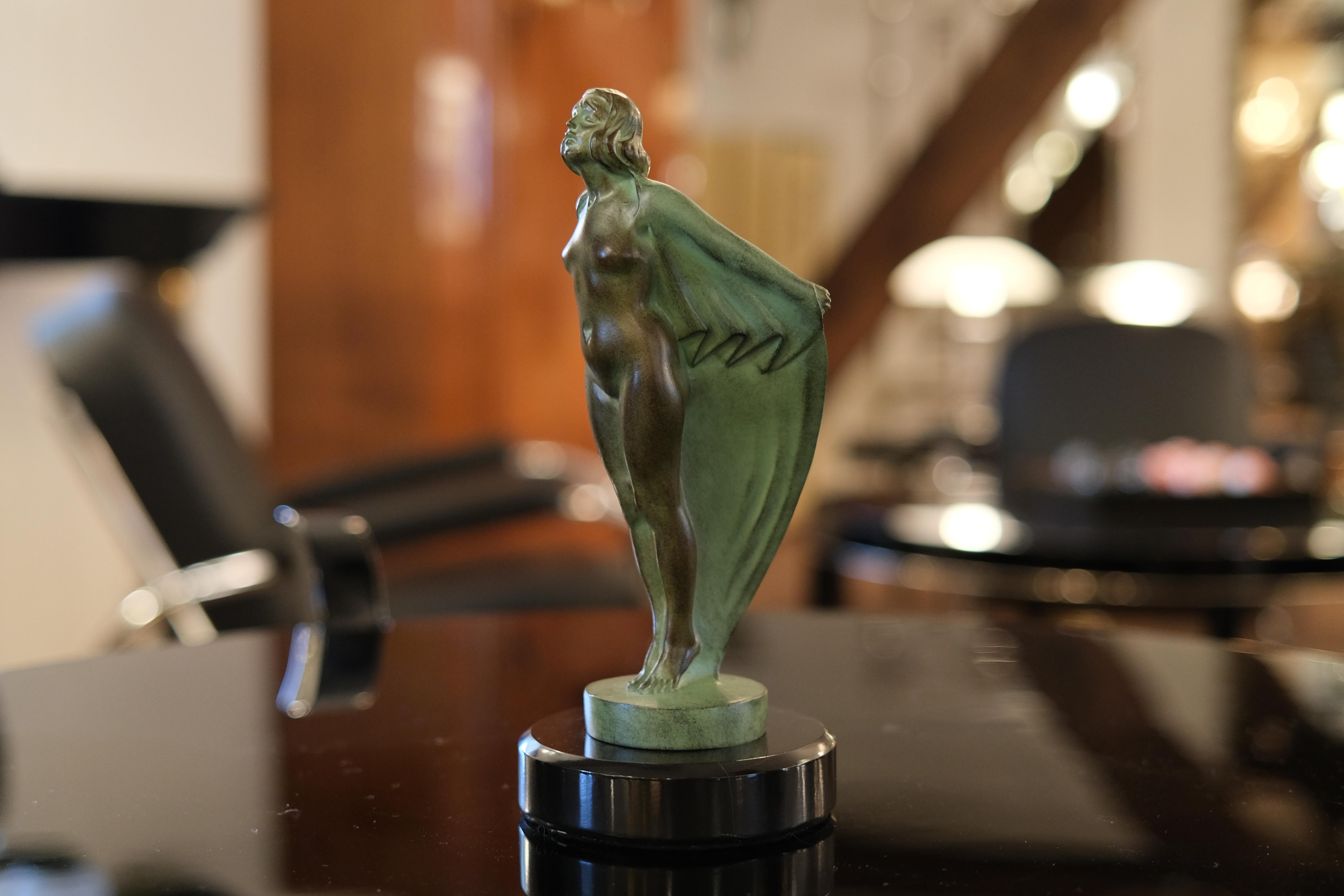 Dynamic presentation of a lady enveloped in a veil. 
Very decorative hood ornament named FEMME AU VOILE (engl. lady at sail) 
This French radiator mascot was designed during the roaring 1920s by “Max Le Verrier” himself 

Original Max Le