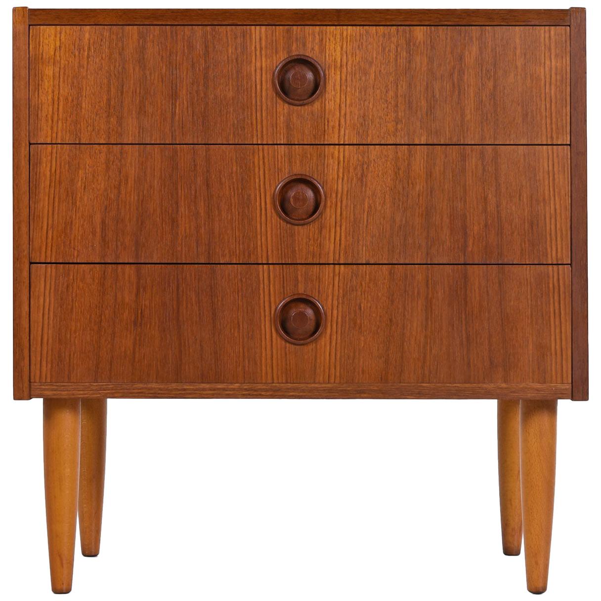 Expertly crafted Mid-Century Modern Danish teak nightstand or bachelors chest of drawers. Three stacked drawers with radio knob style pulls carved from dark tone contrasting solid teak.