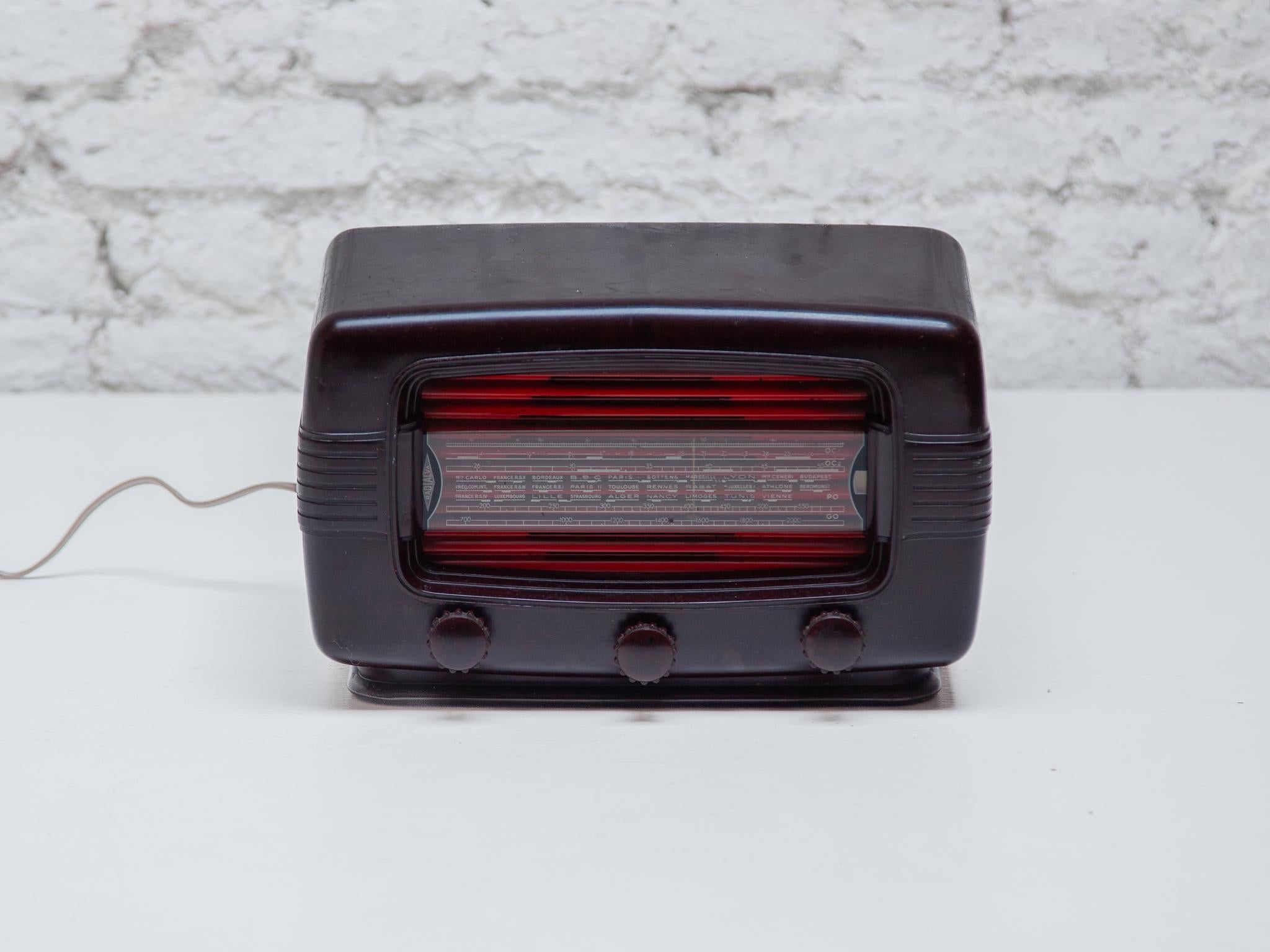 Original made of dark brown bakelite with brown knobs. Behind the glass station shell is a red and black painted metal plate that has been blackened behind the transmitter division. Two scale lights (12V/0.06A) illuminate the scale at both ends. The