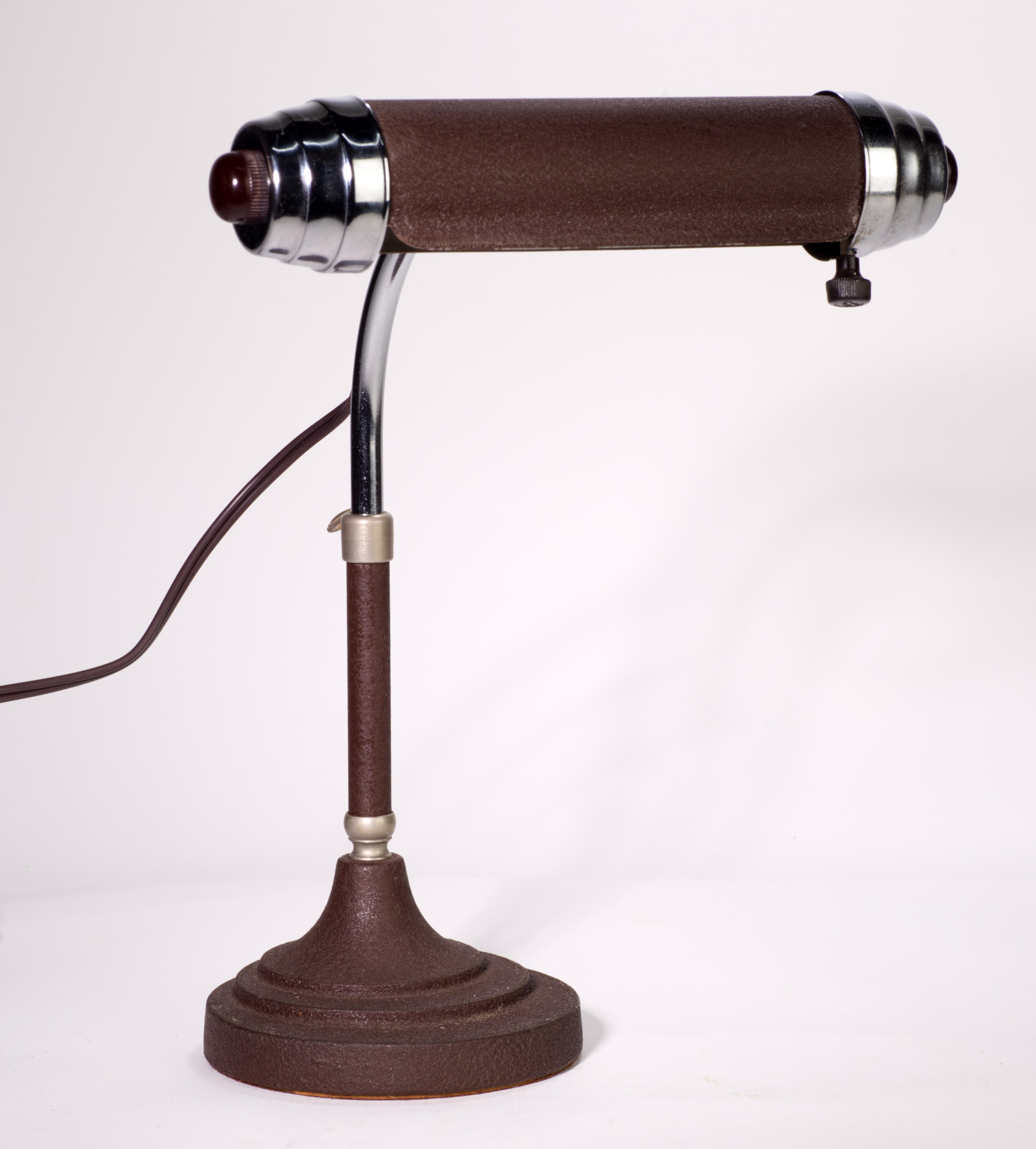 Mid-Century Bankers Lamp from Radionic Trans Co. made between 40s and 60s. Lamp features chrome end caps, Bakelite ends, textured paint and steel.  Arm is adjustable up and down and the head pivots. 
Wire was updated to modern SPT-1 with polarized