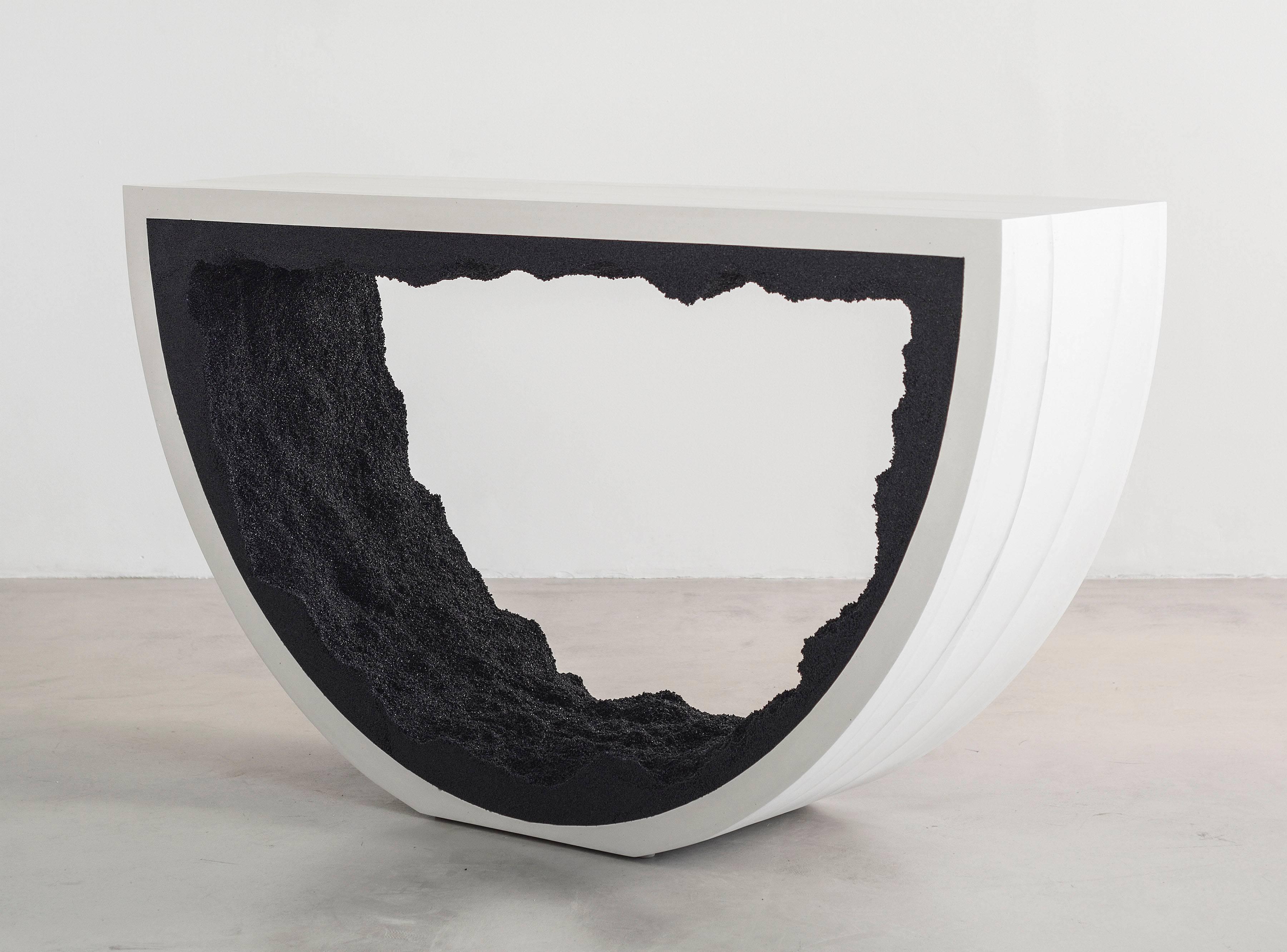 Composed from a combination of materials, the semicircle console consists of a hand-dyed white cement exterior and a rock salt interior. Packed by hand within the smooth white cement, the black silica forms an organic texture to contrast the strong