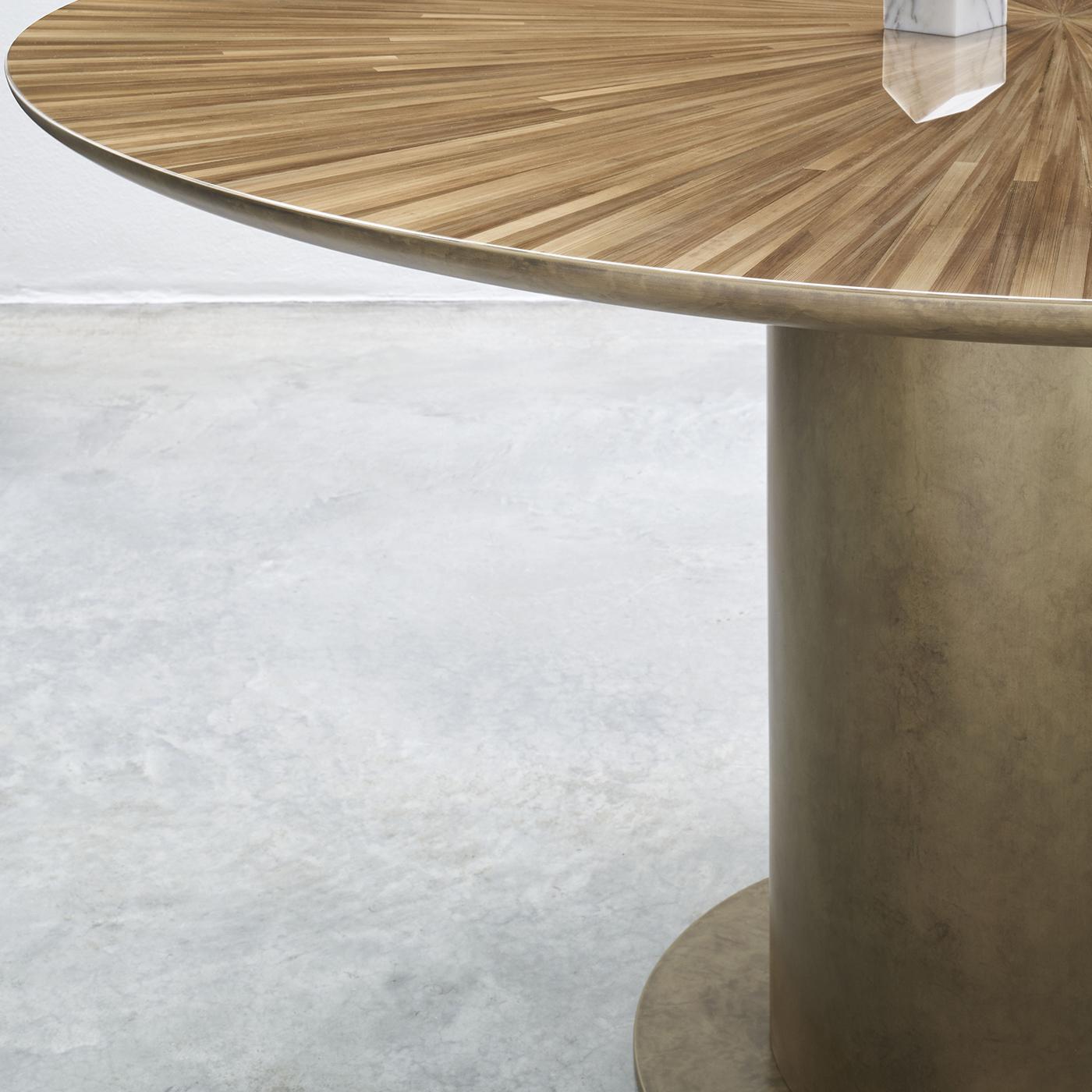 A masterpiece of simple and sculptural geometry, the radius table is designed by Antonio De Marco and Marco Sorrentino. Standing proudly on a monolith base, adorned with liquid metal in an oxidized bronze finish, the table features majestic straw