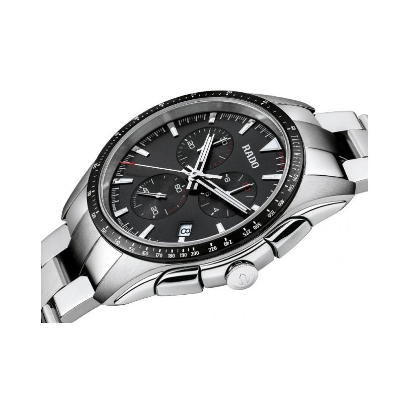 Stainless steel case with a stainless steel bracelet. Fixed stainless steel bezel with a black top ring showing tachymeter markings. Black dial with luminous silver-tone hands and index hour markers. Minute markers around the outer rim. Dial Type: