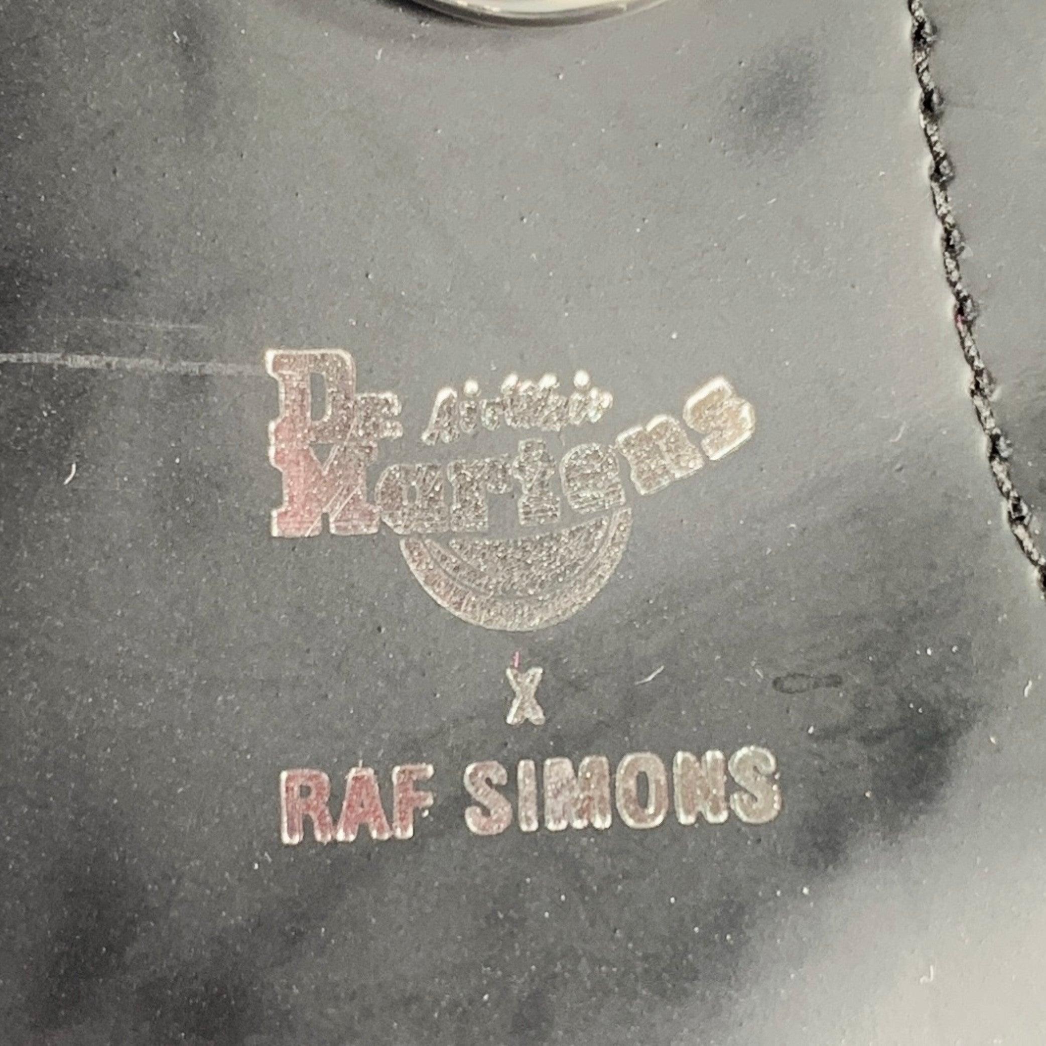 RAF SIMONS x DR. MARTENS boots
in a black leather fabric featuring a silver tone O-ring design, ankle height, rubber sole, and lace-up closure.Excellent Pre-Owned Condition. 

Marked:   9 

Measurements: 
  Length: 11 inches Width: 4 inches Height: