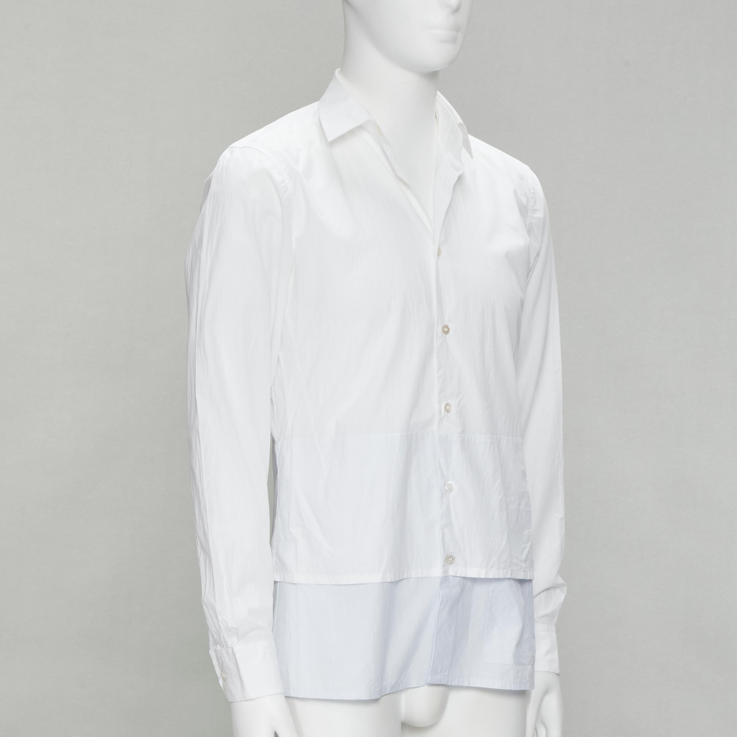 RAF SIMONS white extended layered hem deconstructed shirt EU44 S
Brand: Raf Simons
Designer: Raf Simons
Material: Cotton
Color: White
Pattern: Solid
Extra Detail: Button pocket detail at front left hem.
Made in: Romania

CONDITION:
Condition: