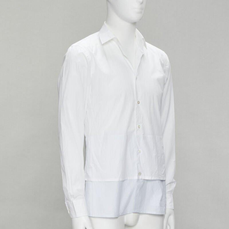 RAF SIMONS camicia bianca con orlo a strati esteso e decostruito EU44 S
Riferimento: EDTG/A00072
Marchio: A. Simon
Designer: A. Simon
Materiale: Cotone
Colore: Bianco, Blu
Modello: Tinta unita
Dettagli extra: Tasca con bottone sull'orlo anteriore