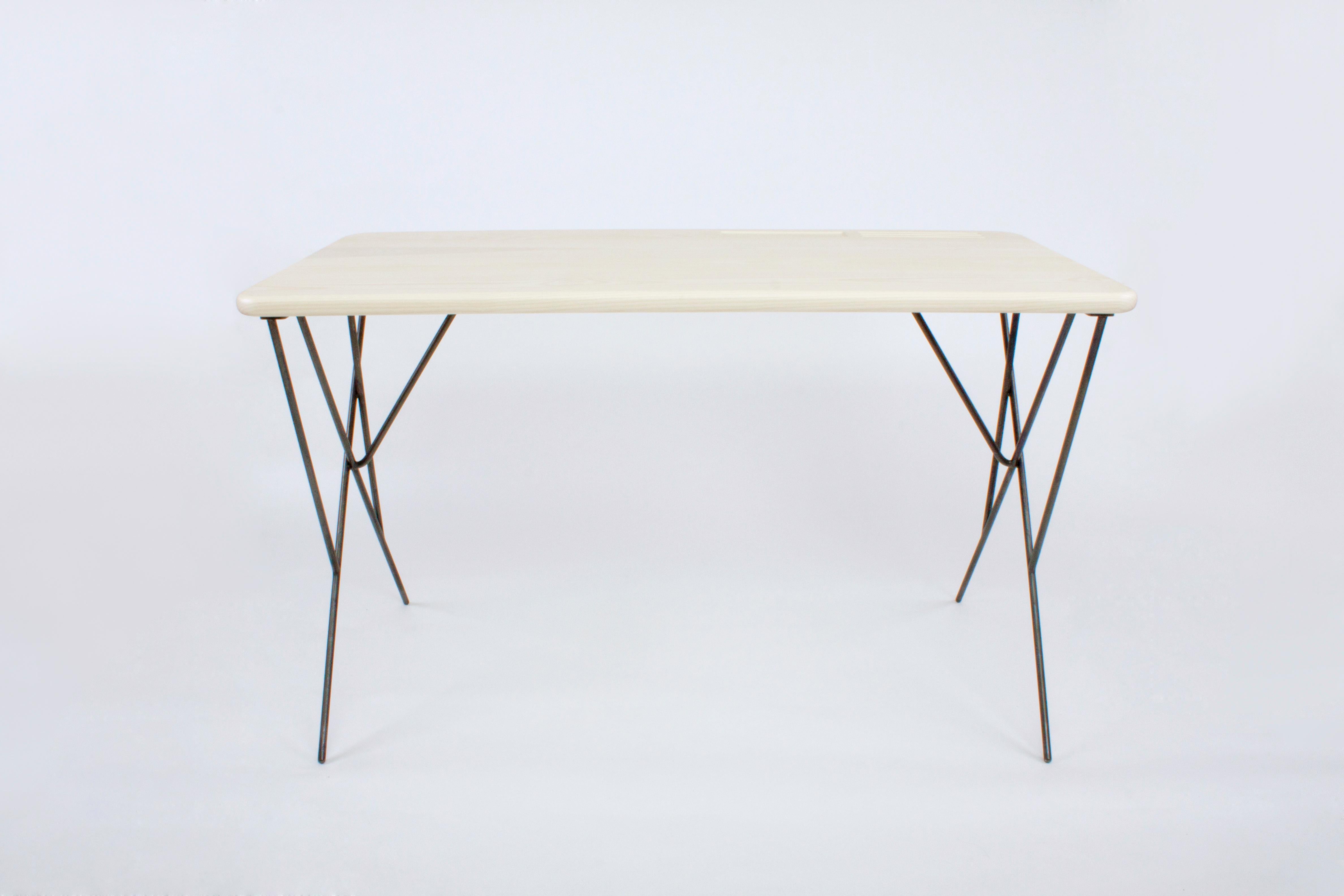 Rafaël is a desk with a very light profile. Interlacing metal rods form the base that holds an Ash top. The desk has pen and storage details on the side.