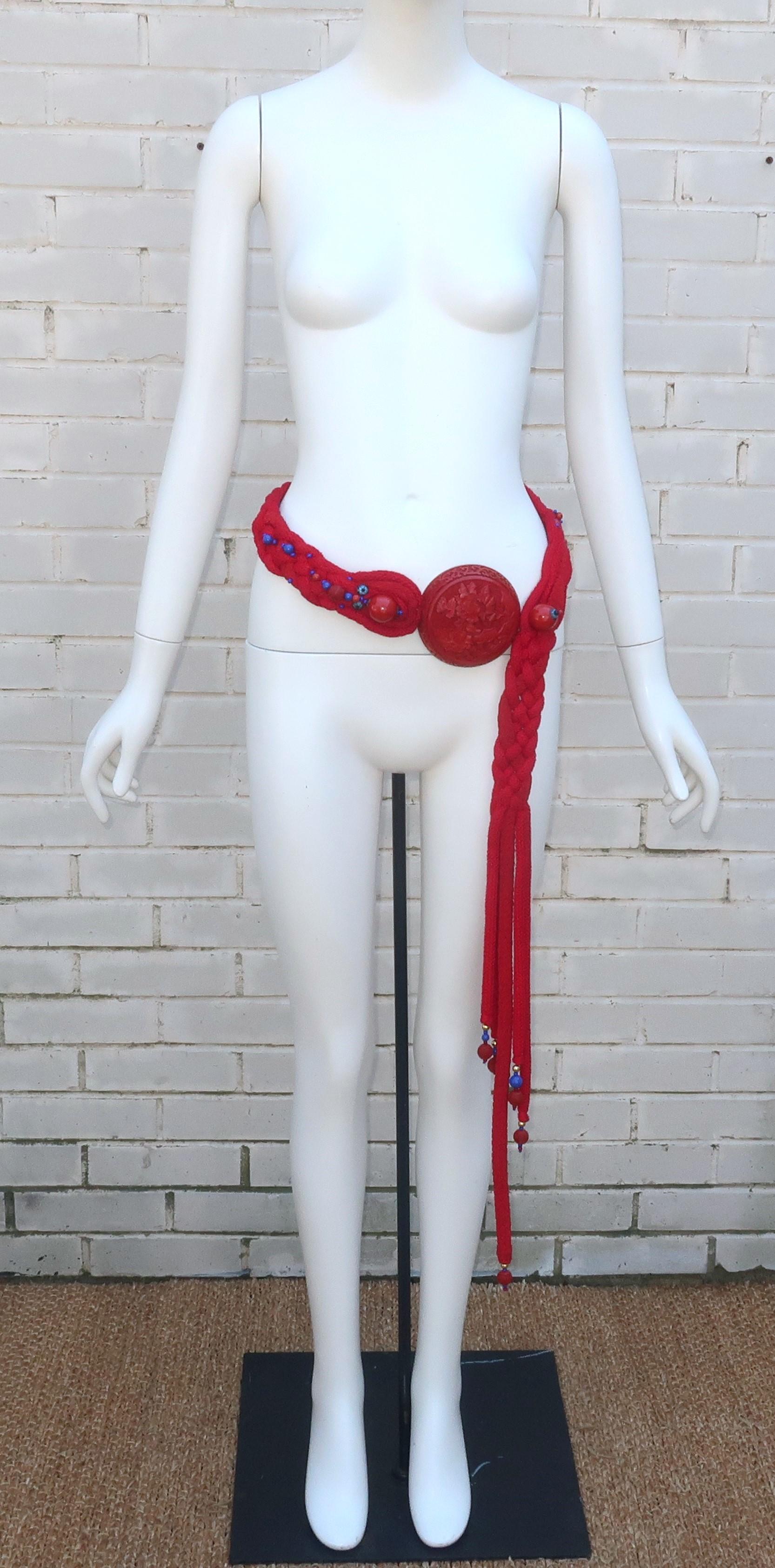 1980's Rafael Sanchez red braided belt with a statement making cinnabar resin medallion, enameled florets and glass beading.  The belt has a distinctive Asian influence and is reminiscent of traditional Chinese regalia.  The cinnabar medallion is