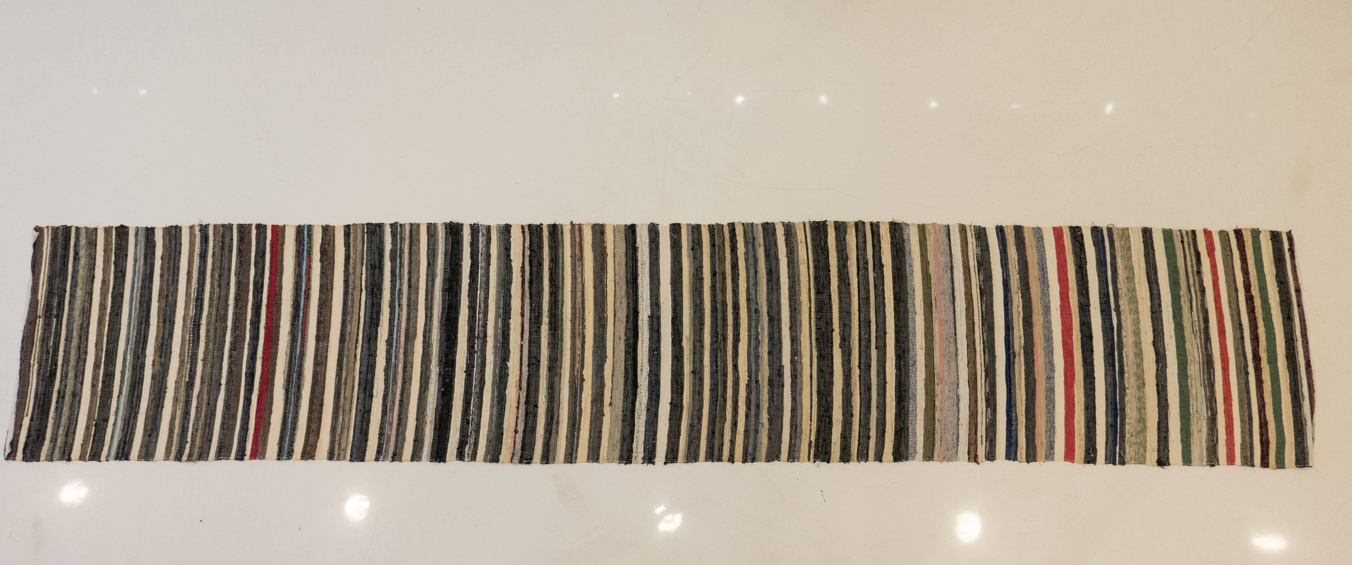 Hand-stitched fabric rag runner showing a succession of multicolor stripes, measuring 152