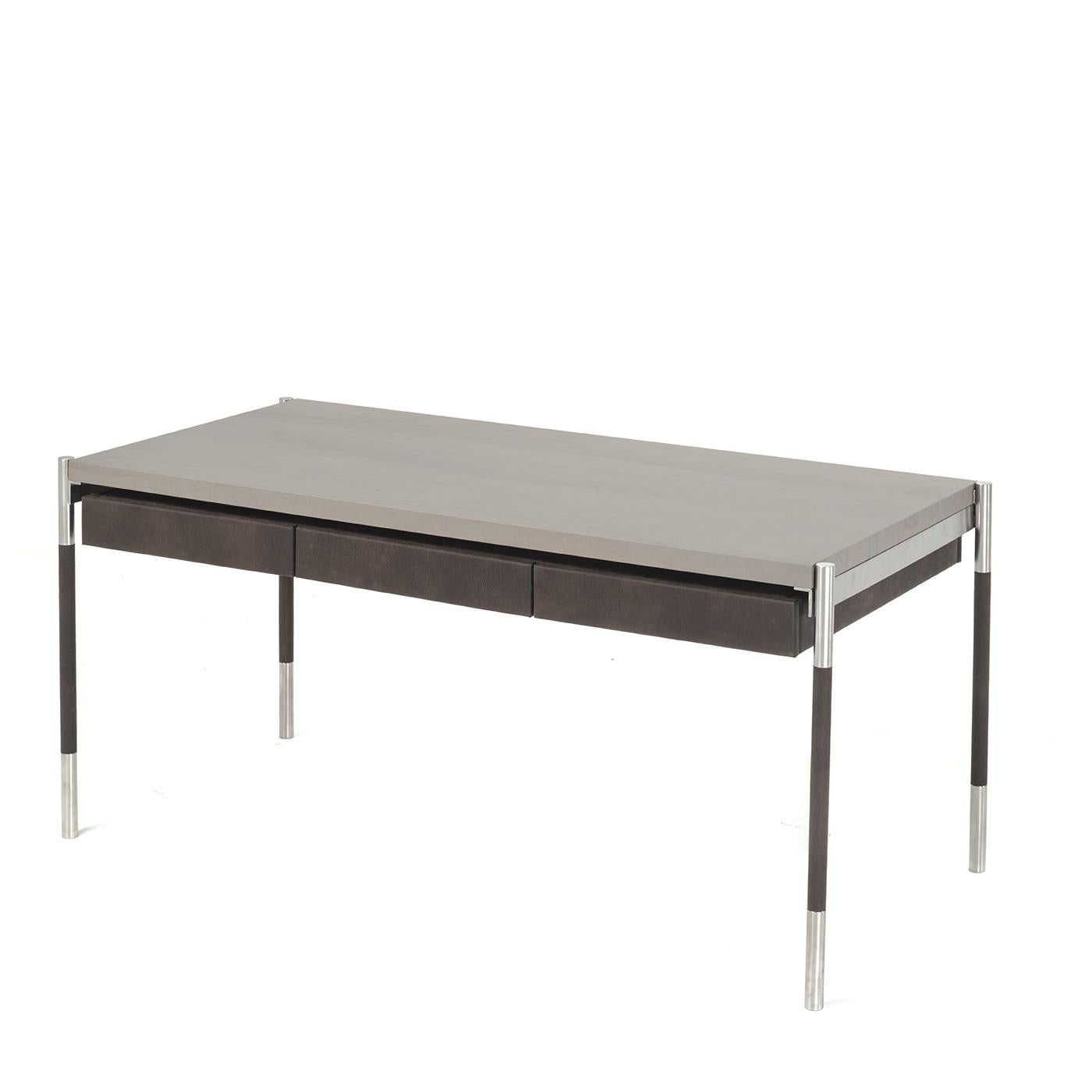 This desk features an elegant dark gray, olive wood top sitting upon a satin stainless steel structure with genuine leather detailing. Three minimalist drawers are also covered and lined in genuine leather. This item is both practical and stylish.
