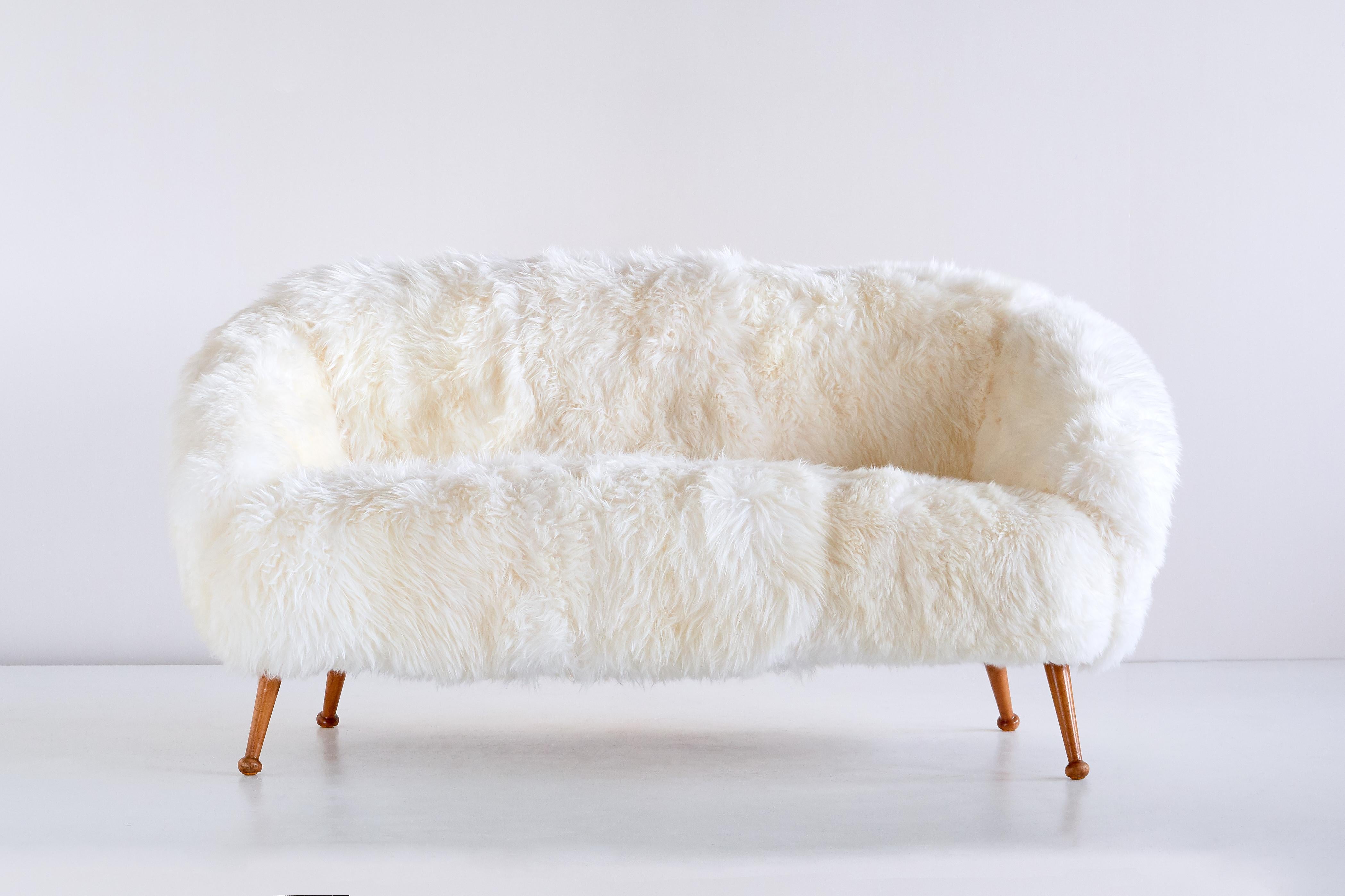 This striking sofa was designed by Ragnar Helsén and produced by AB Stjernmöbler in Herrljunga, Sweden in 1956. The model of the sofa and its matching armchair was named Vinga. The two seat sofa is upholstered in a white long hair sheepskin. The