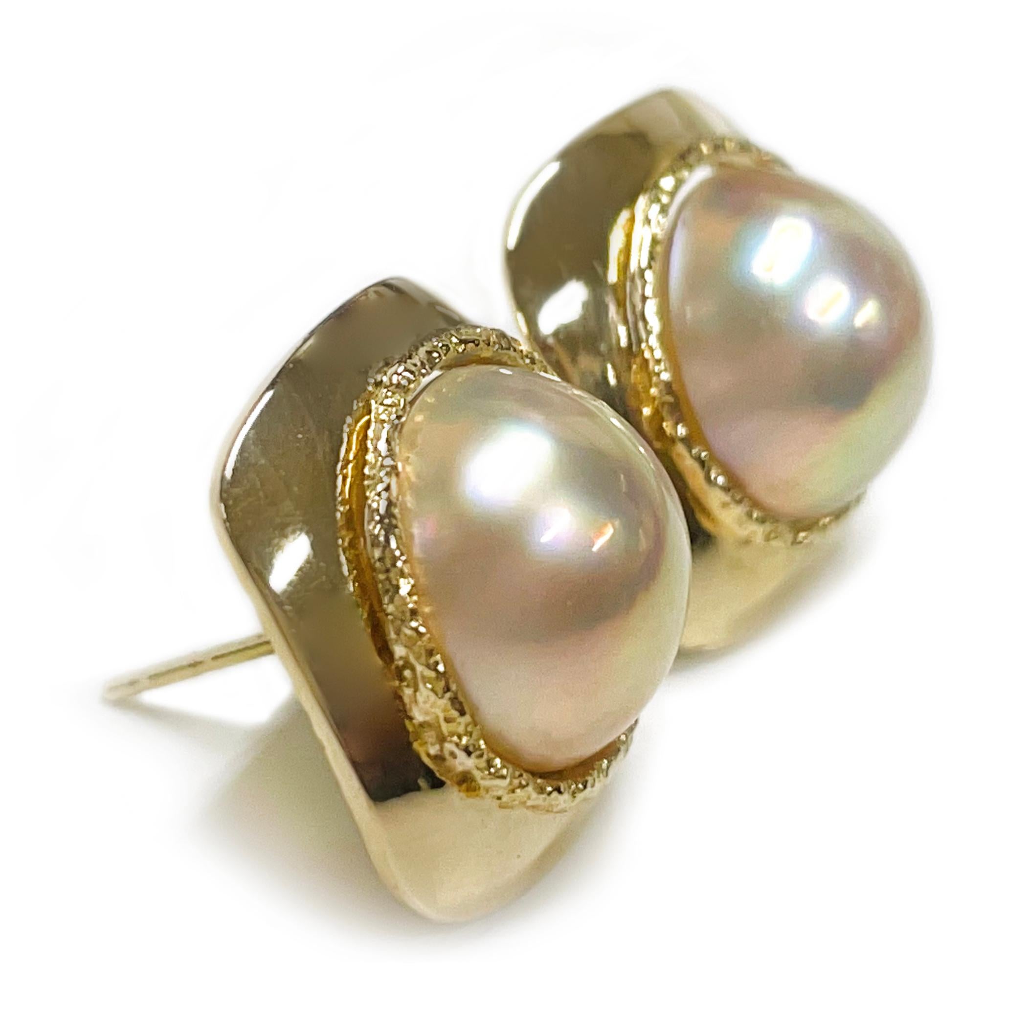Orecchini di perle Mabe Ragnar in oro giallo 14 carati. Gli orecchini presentano perle Mabe color crema da 11 mm incastonate in un castone aperto. Le perle rotonde hanno una buona lucentezza e una colorazione rosa e verde. Ogni lunetta è circondata