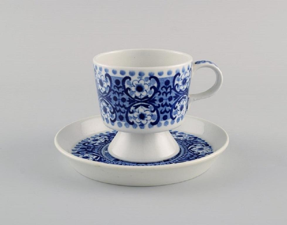 Raija Uosikkinen pour Arabia. 9 tasses à café en porcelaine Ali avec soucoupes. 
Décoration florale bleue. 1960s.
La tasse mesure : 6.7 x 6,7 cm.
Diamètre de la soucoupe : 12 cm.
En parfait état.
Estampillé.