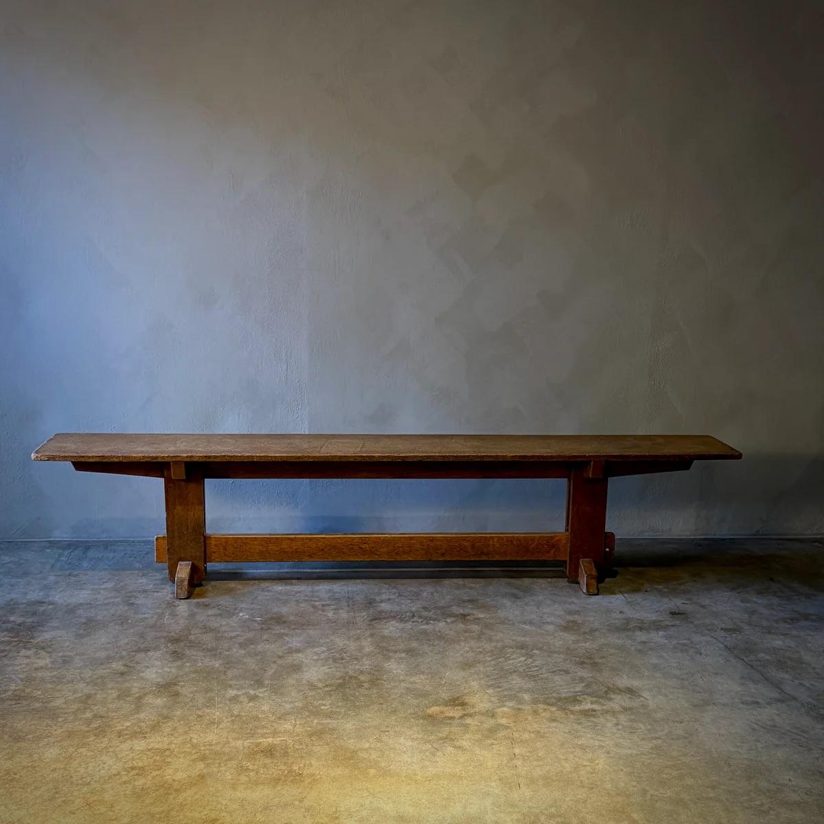Ce banc de chemin de fer présente un design robuste et utilitaire avec une patine usée par le temps qui témoigne de son histoire. Son assise allongée et sa construction solide reflètent une forme pratique mais élégante, idéale à la fois comme siège