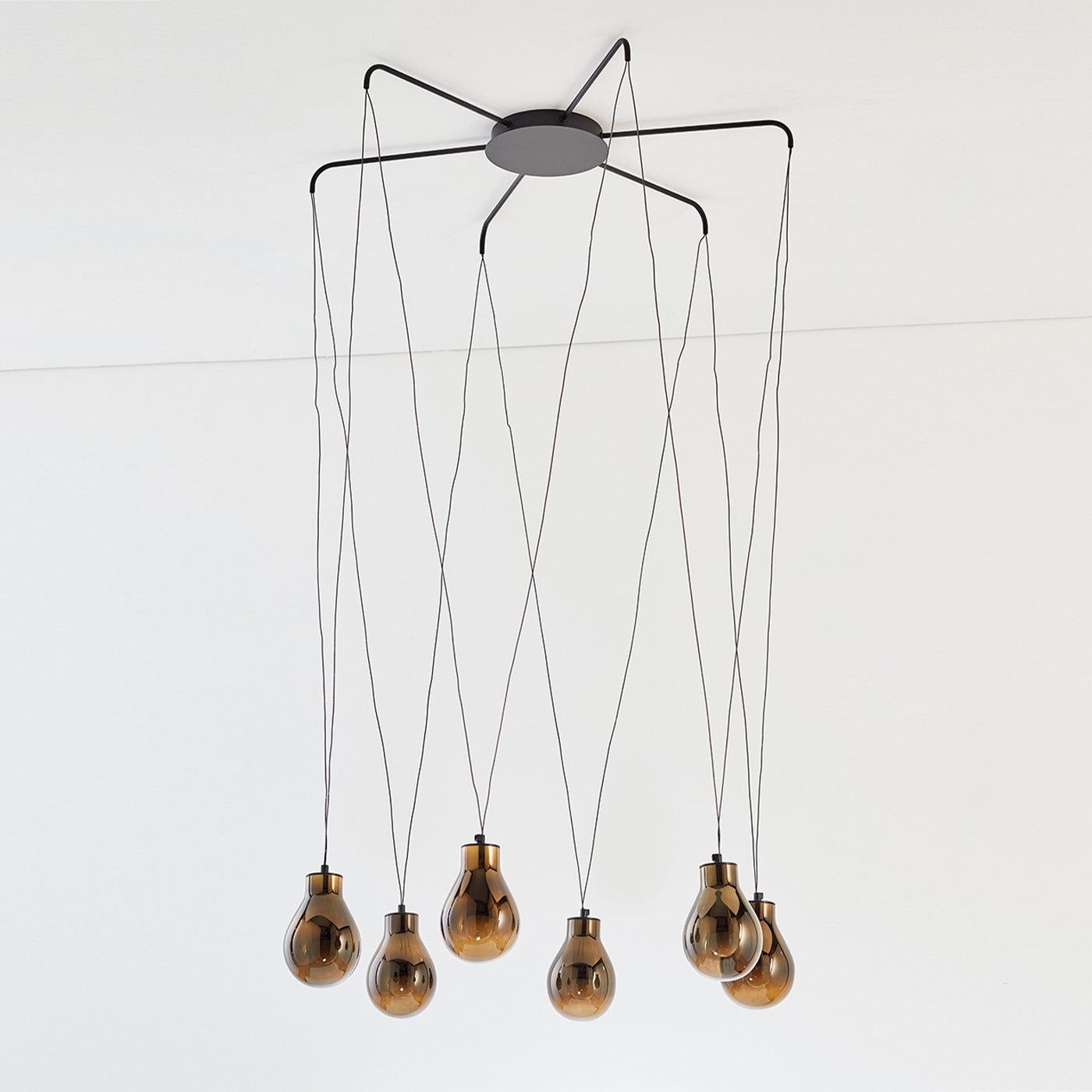 Part of an extremely elegant collection of minimalist design, this chandelier draws inspiration from the evocative character of rain. Light and sleek, it features a matte black metal structure from which hang six pairs of V-shaped threads ending
