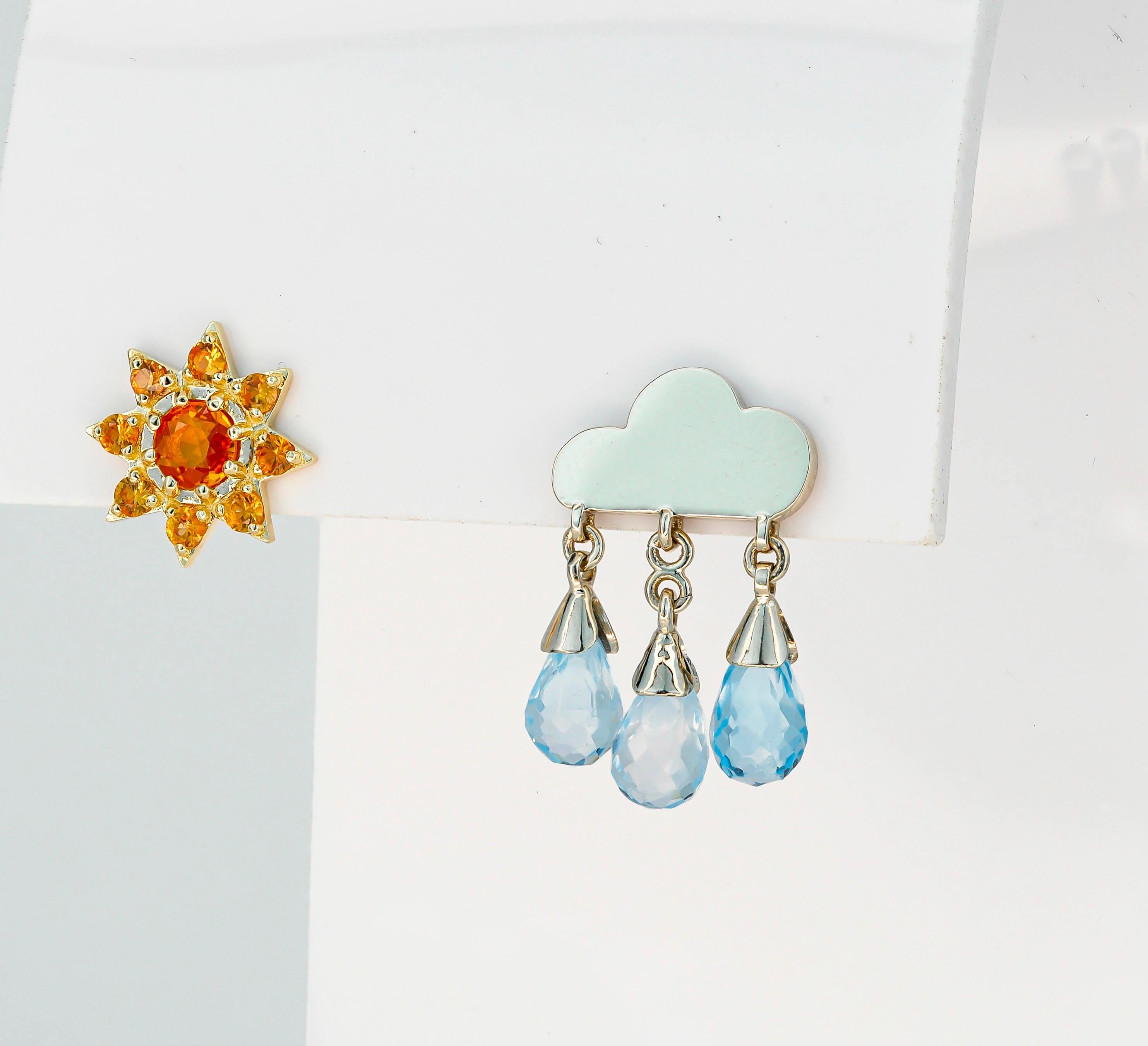 Rain and sun 14k gold earring studs. 
Mismatched earrings. Weather inspired earrings. Natural topaz, sapphire studs. Teardrop earrings.

14k yellow and white gold
Weight: 3.15 g. 

1. Rain cloud
white 14k gold
Size: 19x12mm
Gemstones:
3 topazs, blue