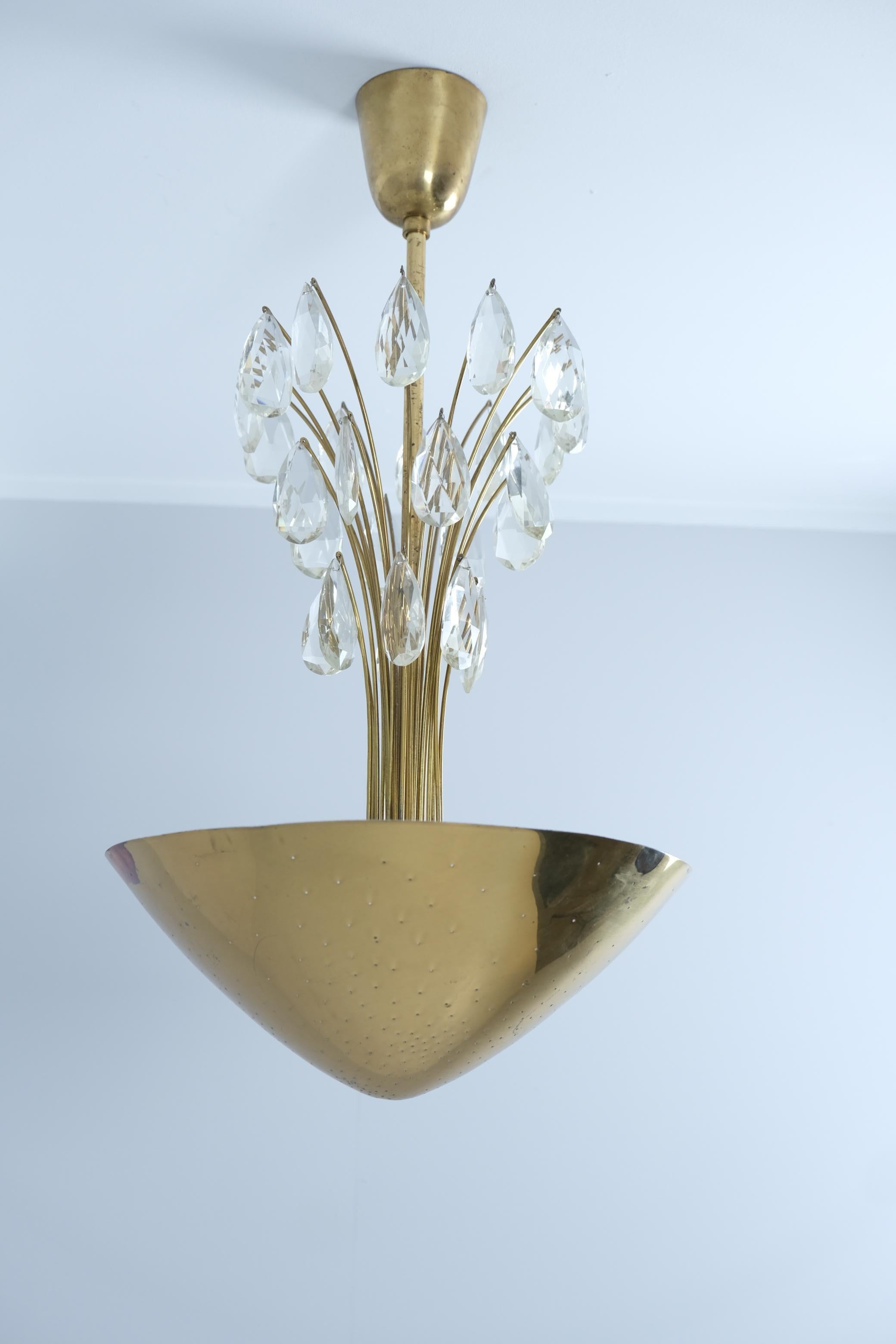 A beautiful ceiling lamp by Lisa Johansson-Papé brilliantly combining a classical touch with the modernistic perforated brass design. The crystals hang like rain drops and are beautifully illuminated by the up-light from inside the perforated brass