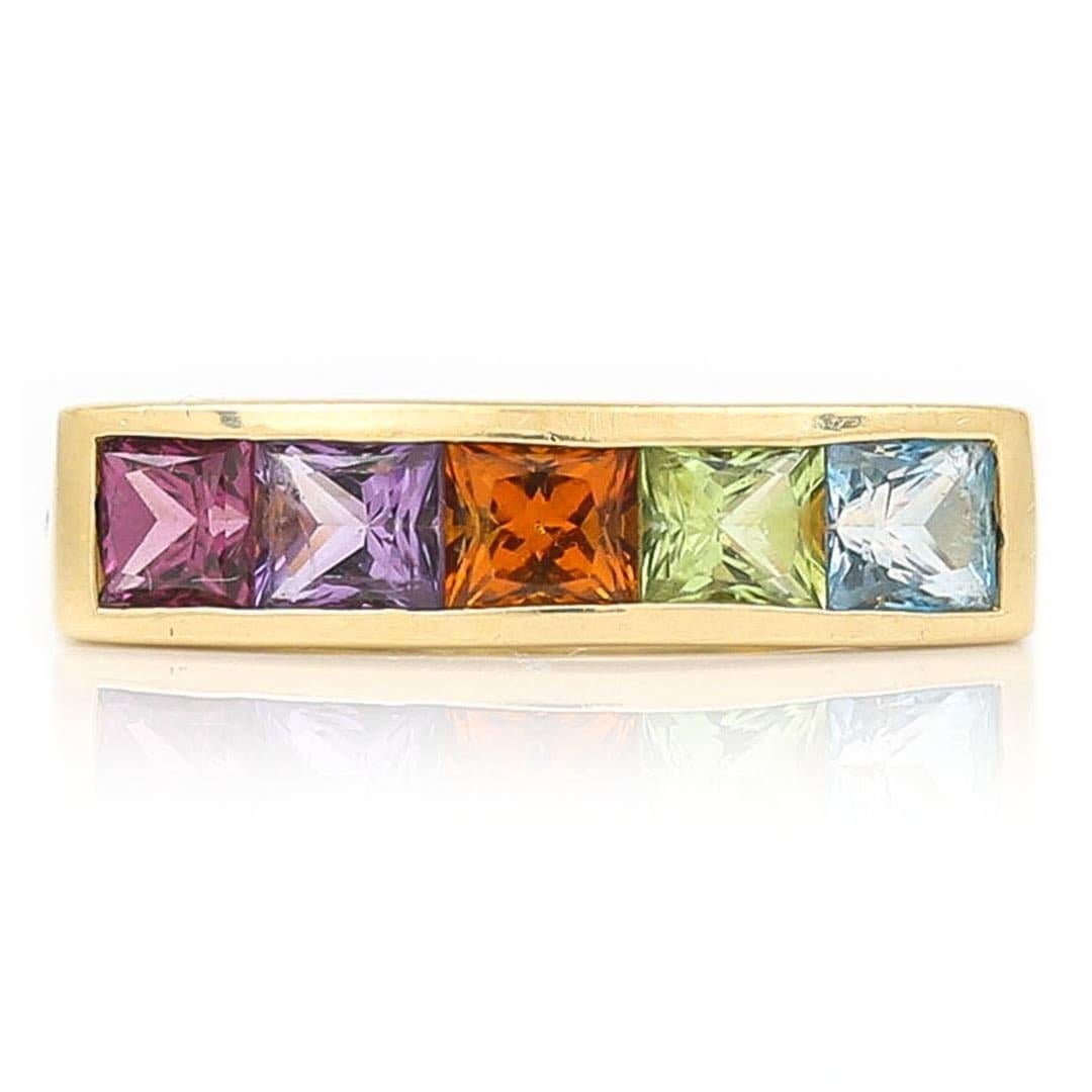 Ein sehr stilvoller und farbenfroher Ring aus 18 Karat Gelbgold, besetzt mit 5 lebhaften Edelsteinen im Prinzessschliff, darunter Blautopas, Peridot, Citrin, Amethyst und Granat. Die Farbkleckse lassen sich hervorragend mit verschiedenen Ringen und