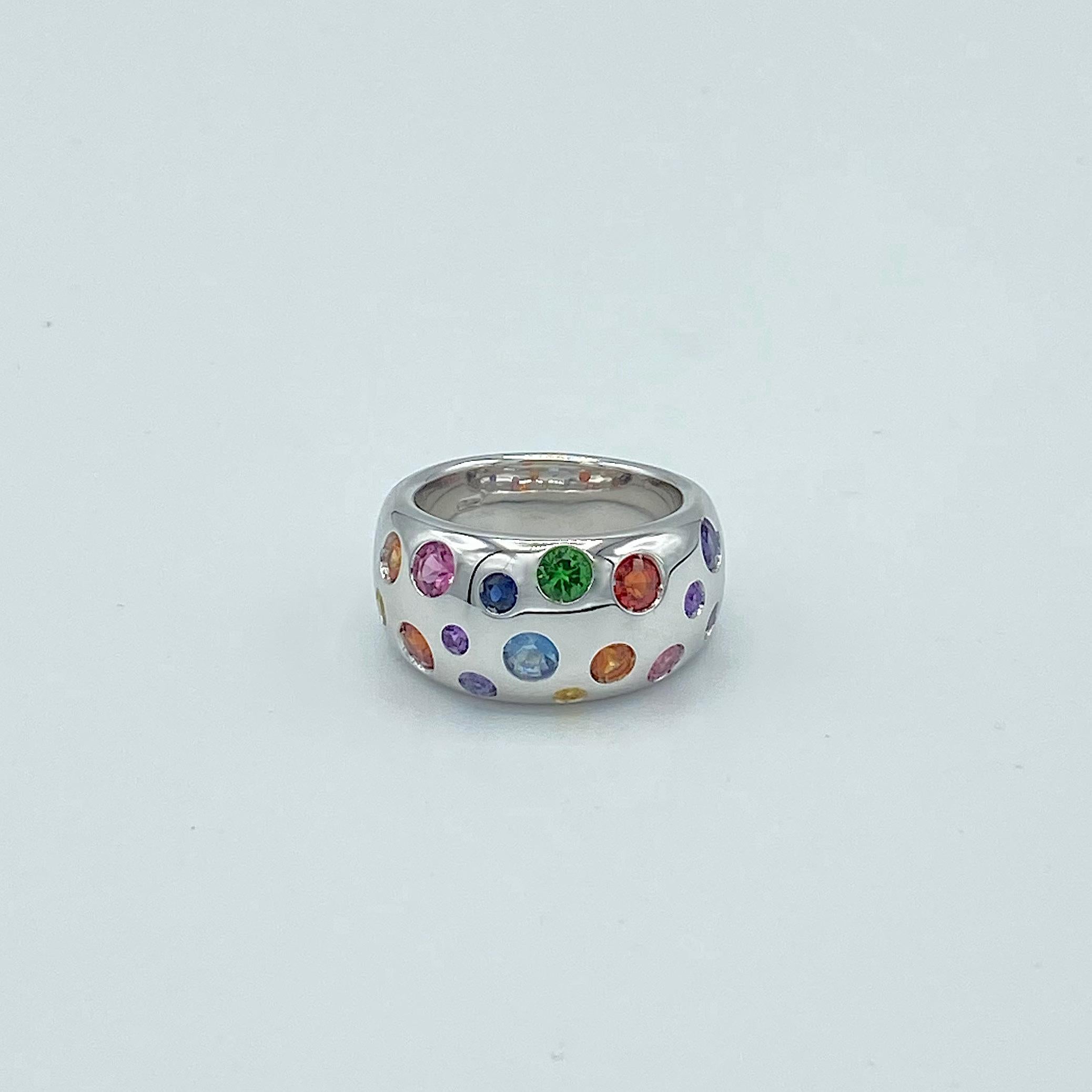 Rainbow Sapphire Aquamarine Amethyst Semiprecious Tsavorite 18KT Gold Band Ring
This white gold band ring is set with sapphires and semi-precious stones of different sizes and colors that follow the nuance of the rainbow.
The stones are: tsavorite,