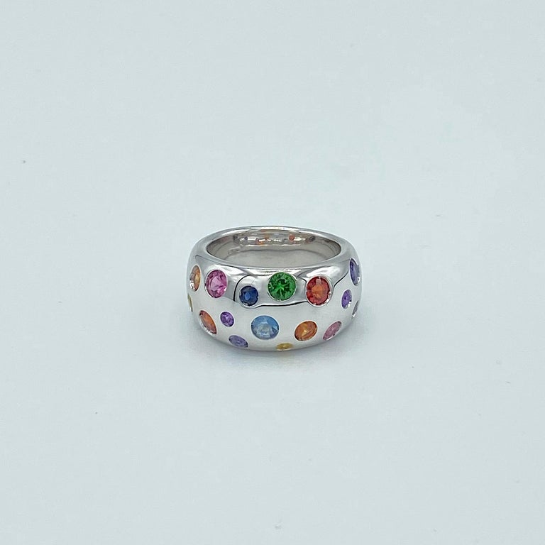 This white gold band ring is set with sapphires and semi-precious stones of different sizes and colors that follow the nuance of the rainbow.
The stones are: tsavorite, yellow, orange, red sapphire, fuchsia tourmaline, amethyst, iolite, blue