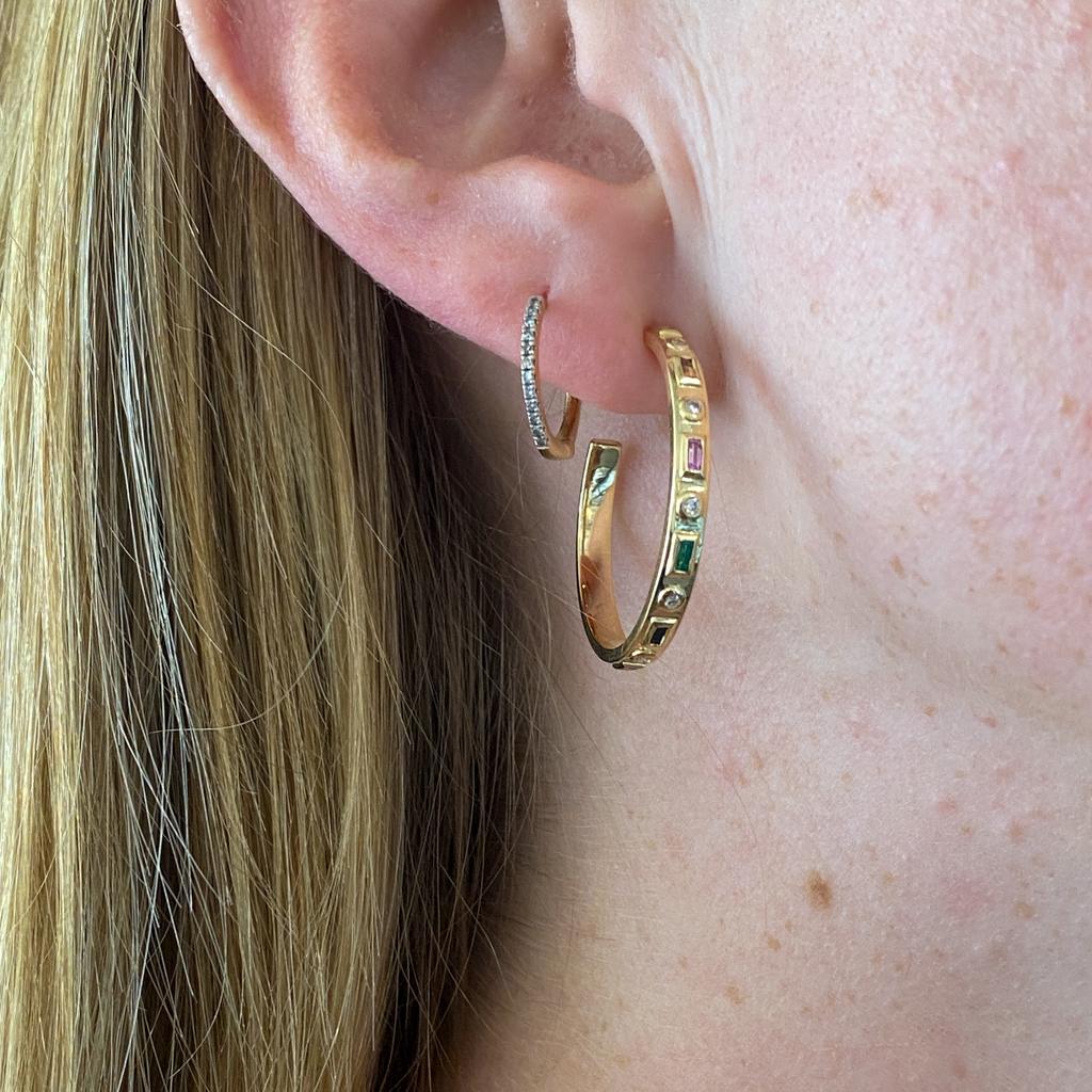 Hoop earrings have a classic look and a timeless appeal. These earrings have a beautiful variation with rainbow colors of baguette sapphires alternating with round diamonds down the center of the hoops. The yellow gold gives the hoops a warm
