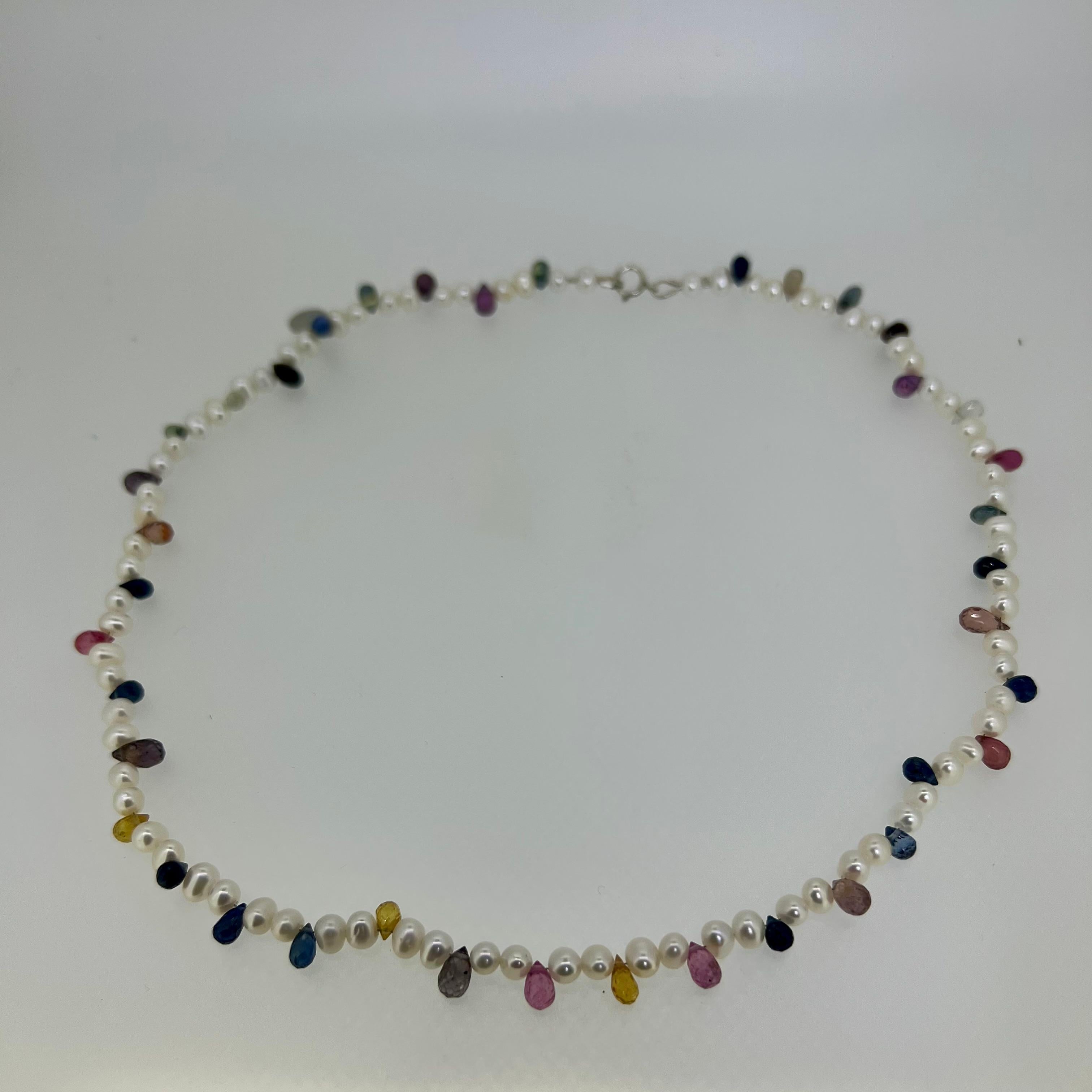 
Delicate yet dazzling, this 40 cm (15.7 in) necklace features a strand of petite AAA-grade freshwater pearls, each chosen for its luminous sheen and flawless surface. Interspersed with vibrant briolette-cut sapphires in a full spectrum of rainbow
