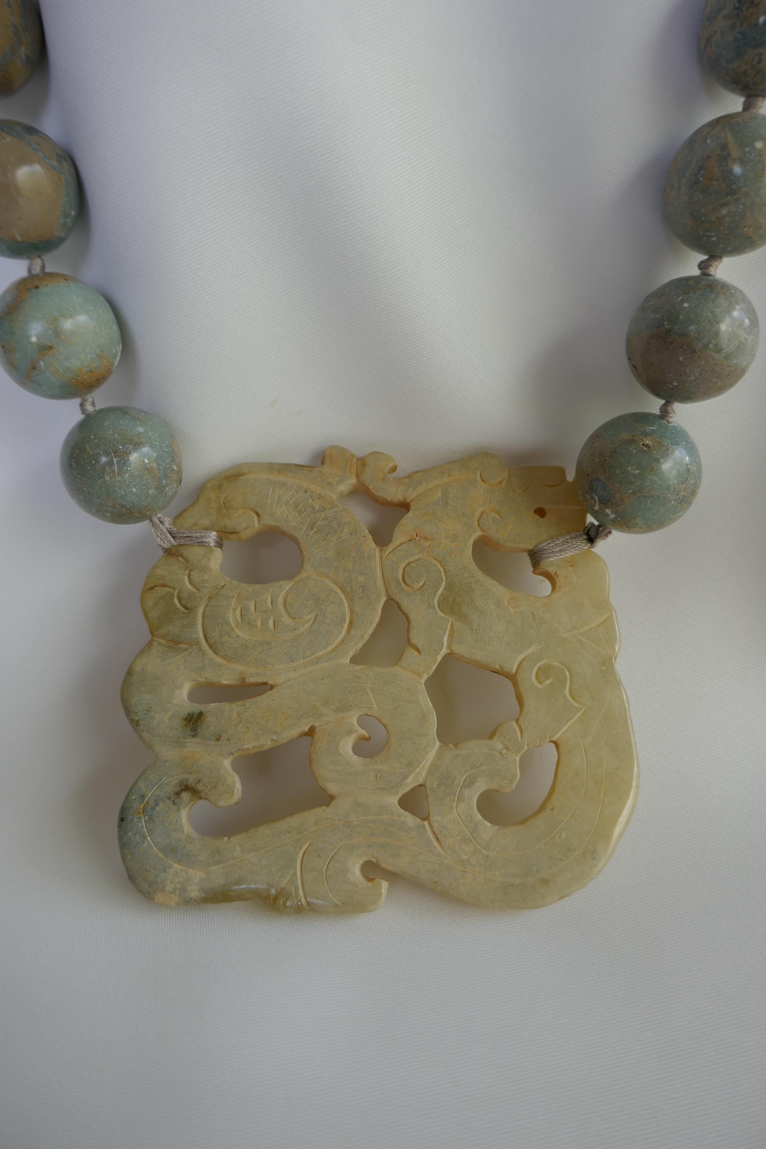 A statement necklace!!! This 20mm forest jasper (stone tonality: beiges sage greens) necklace has a carved milky white agate dragon piece with a 925 oxidized sterling silver clasp.  The necklace is 25 1/2 inches long.   It is strung on beige silk