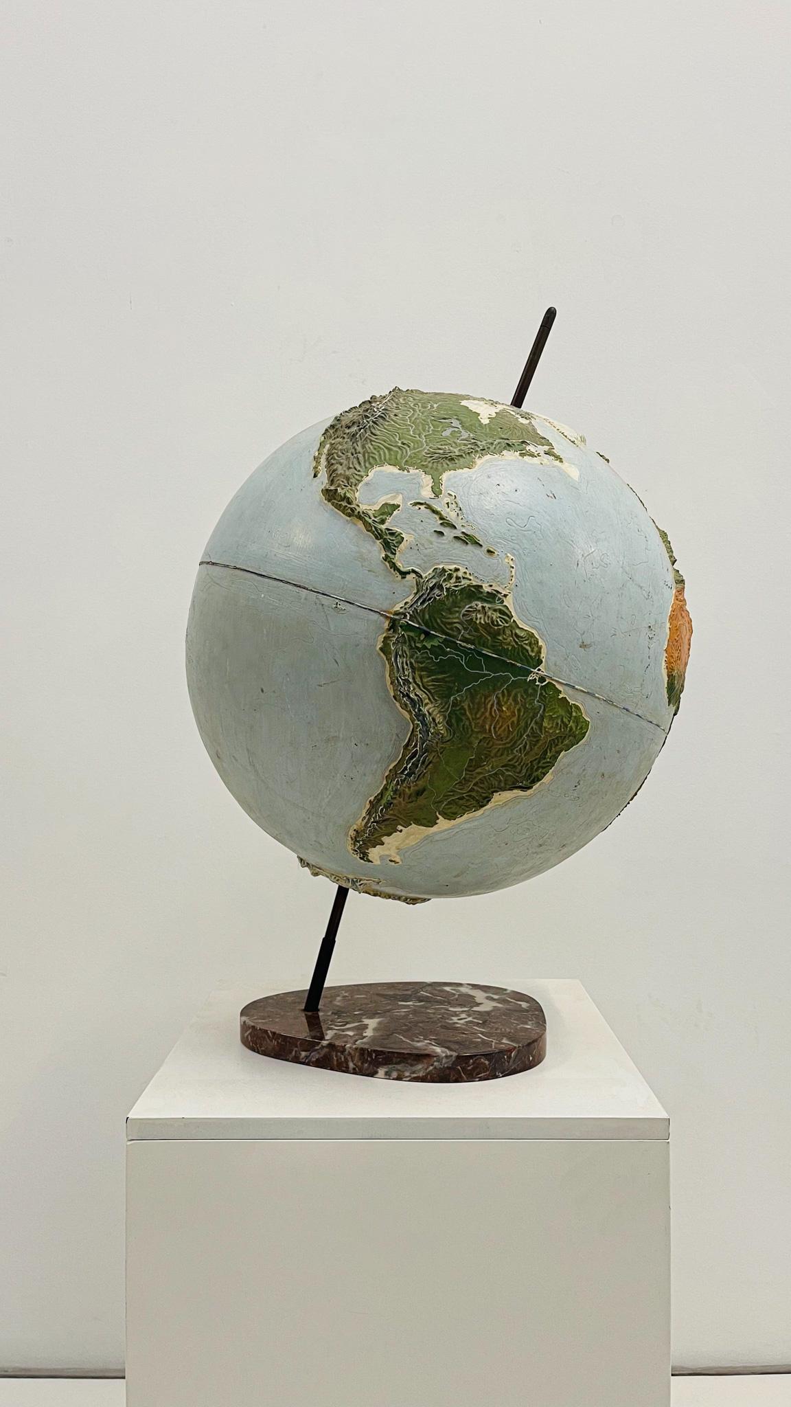 This French Earth globe, attributed to Jacques Adnet, is a stunning decorative piece that blends artistry with craftsmanship. Made of plaster with raised polychrome decoration, it features intricate topographical reliefs that add depth and texture