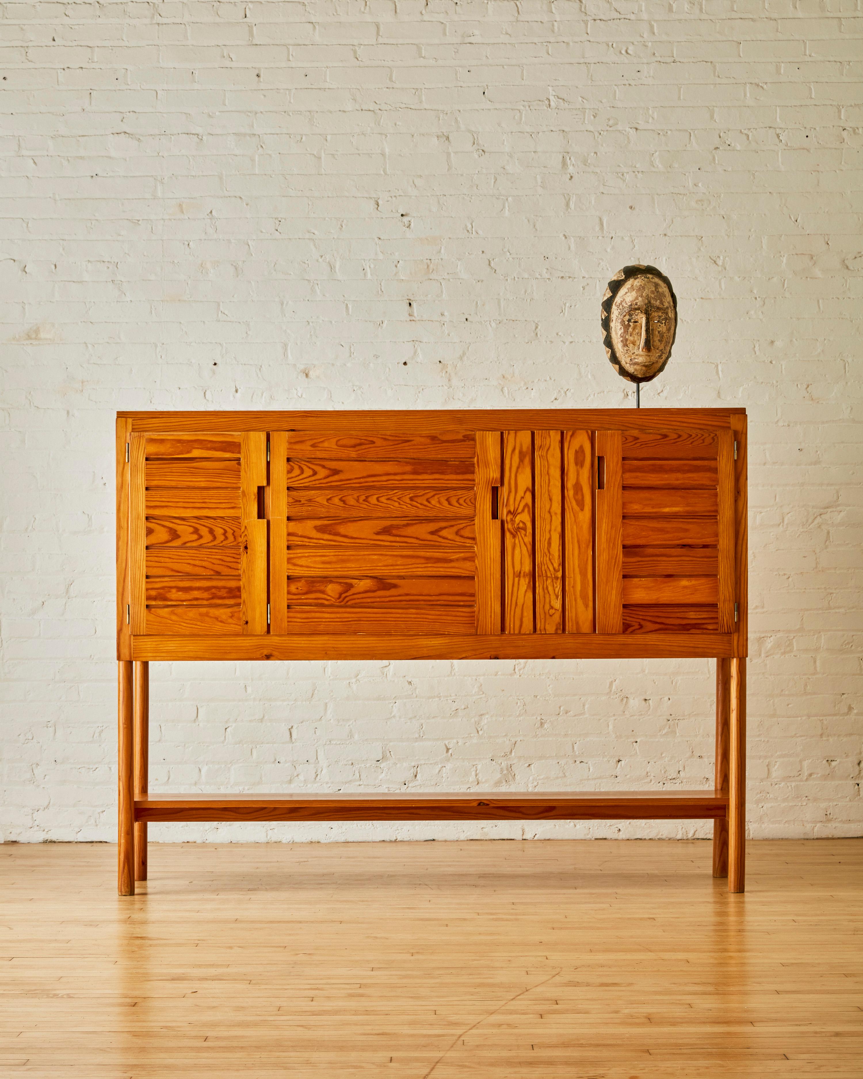 Raised Three-Door Cabinet by Pierre Gautier Delaye, with brass screw details and an elevated design.

Pierre Gautier-Delaye was an important mid century designer in France, trained at the Paris School of Decorative Arts. Delaye initially started