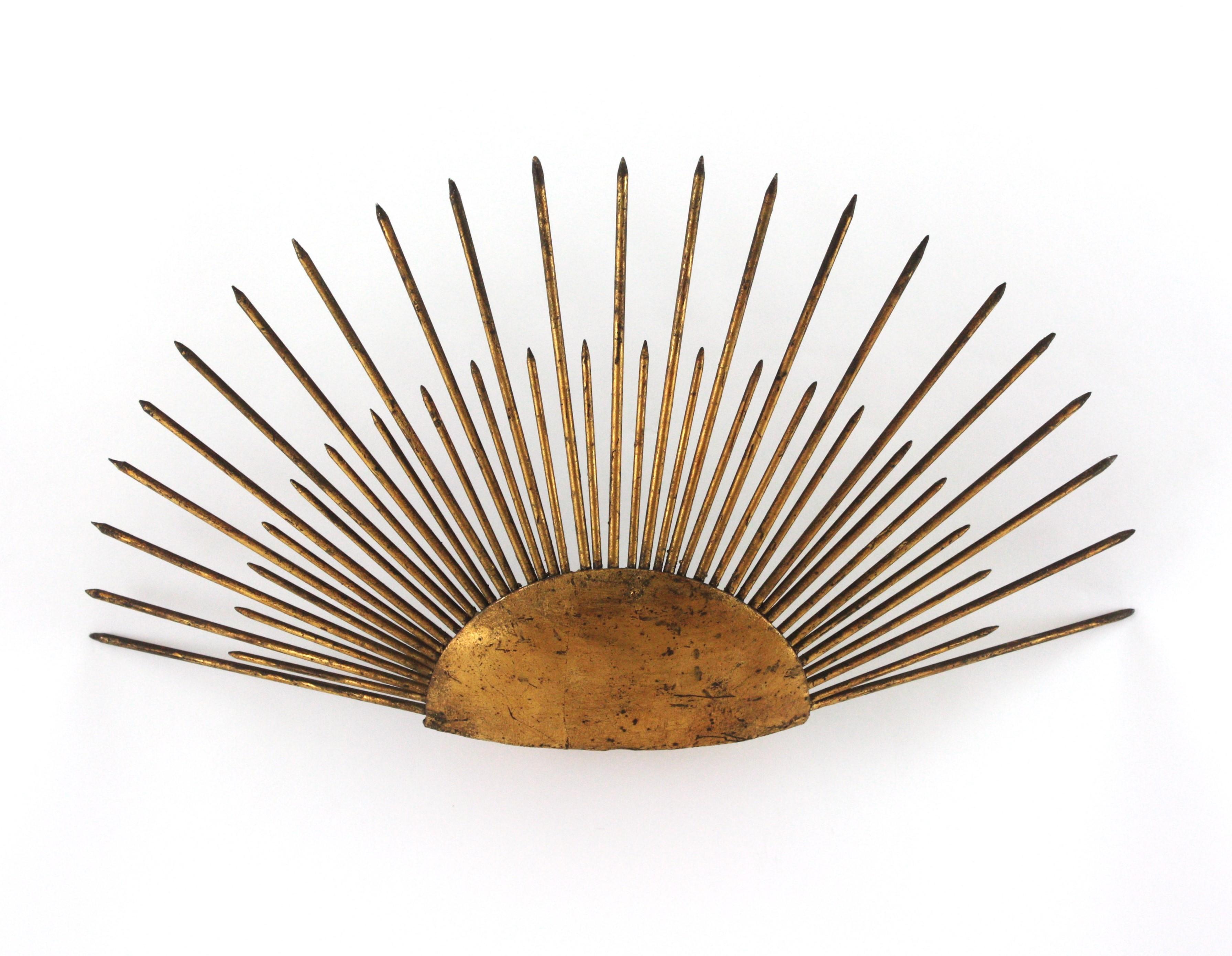Unusual half sunburst shaped wall sconce with nail accents from the late Art Deco period, France, 1940s-1950s.
This raising sun sunburst wall light is highly decorative due to its design with pointed spikes raising from a semi sphere panel.
It has a