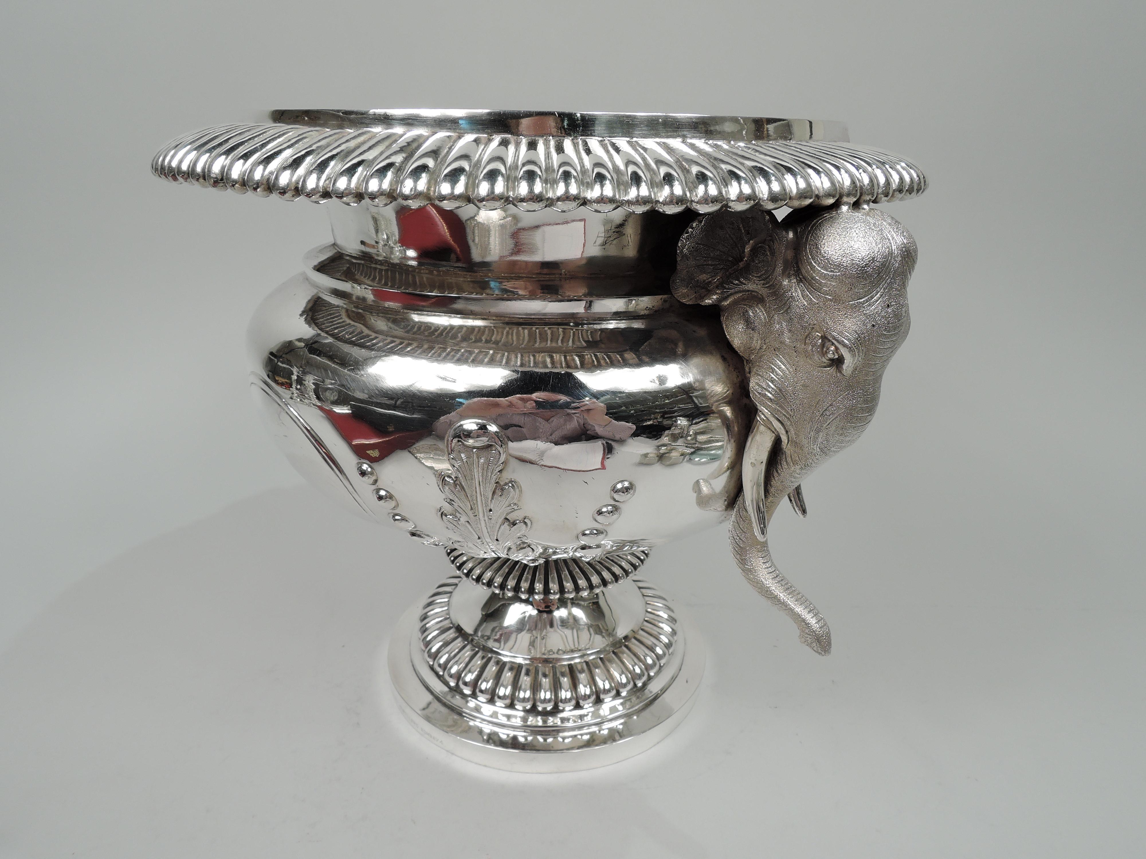 Indian silver wine cooler, ca 1920. Bellied bowl with wide rim on short support with flange flowing into stepped foot. Classical form with bold gadrooning and further enlivened with elephant head side mounts with saggy irregular ears and gracefully