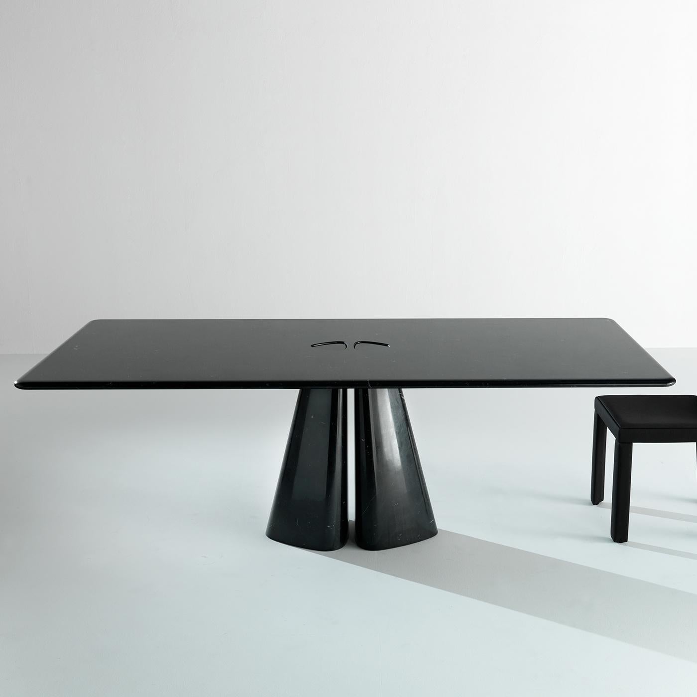 This stunning dining table is entirely made of black marble. A thick rectangular marble top with rounded edges is supported by a unique based formed by two thick angular blocks of the same marble as the top. This is a gorgeous piece that will be a