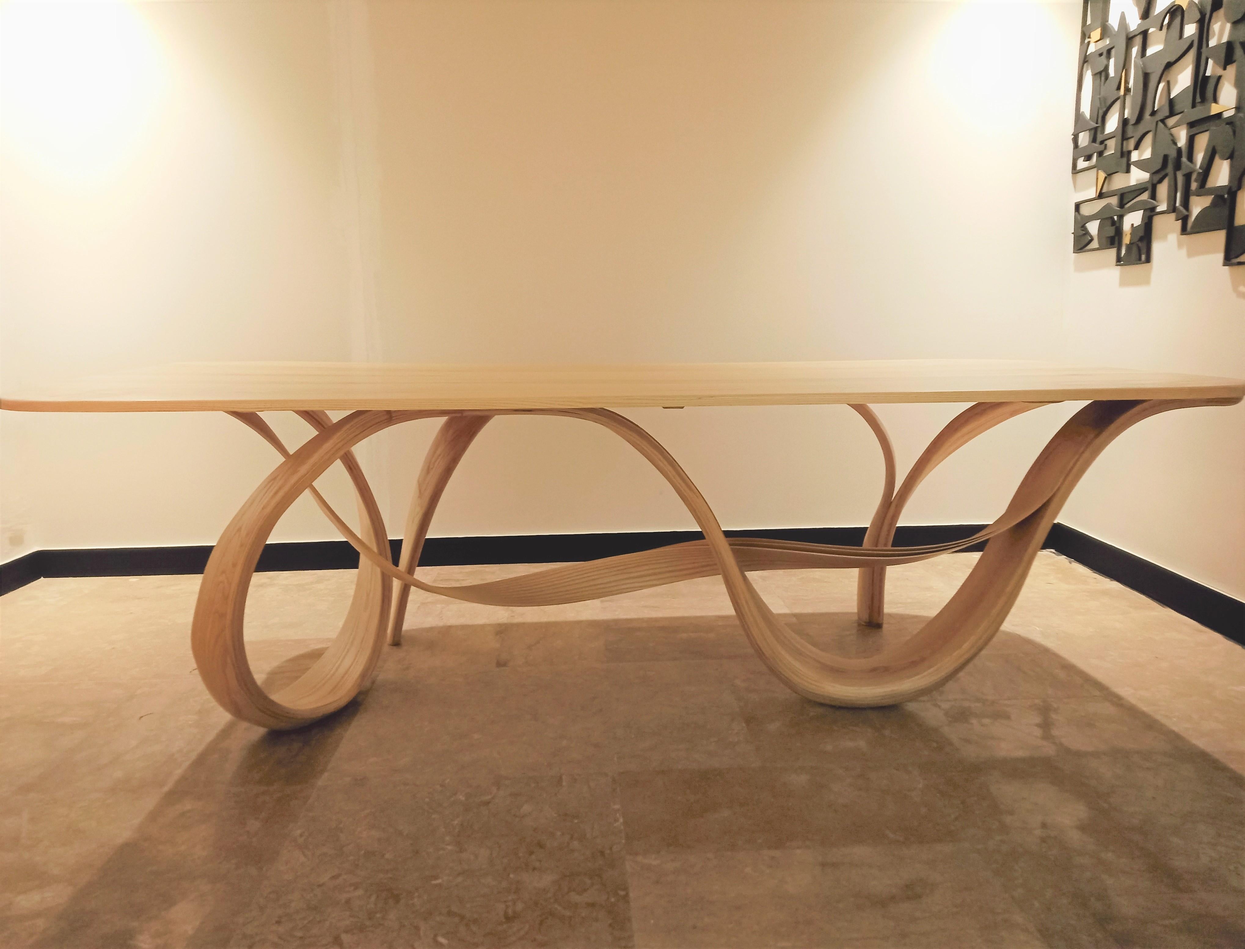 Selene, in Greek, means the moon, is a dining table crafted by bending solid Ash wood. The studio tried to mimic the design elements of nature. All the forms at the base are genteelly twisting and turning into each other while holding up the