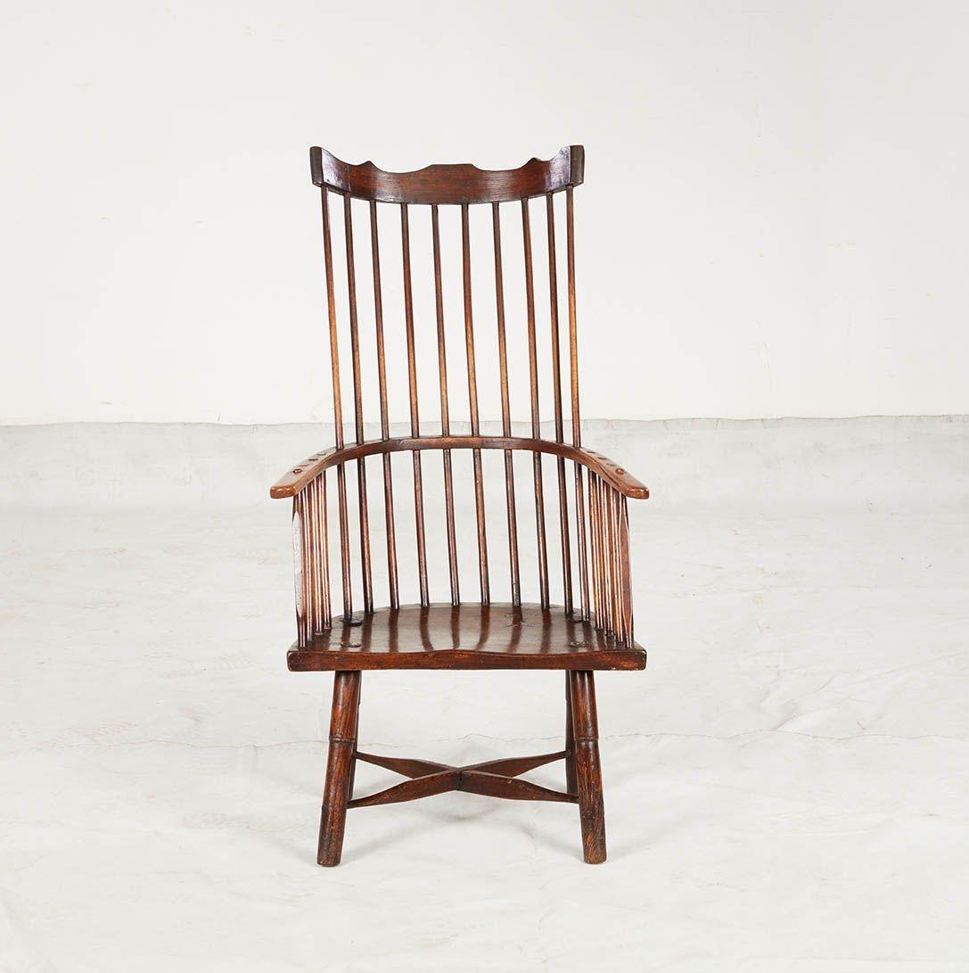 Fauteuil windsor à dossier en peigne, avec une inclinaison remarquable et confortable et un dossier en arc incurvé, avec une traverse supérieure de forme décorative sur de longs fuseaux, un bras continu incurvé très usé, et une assise de forme douce