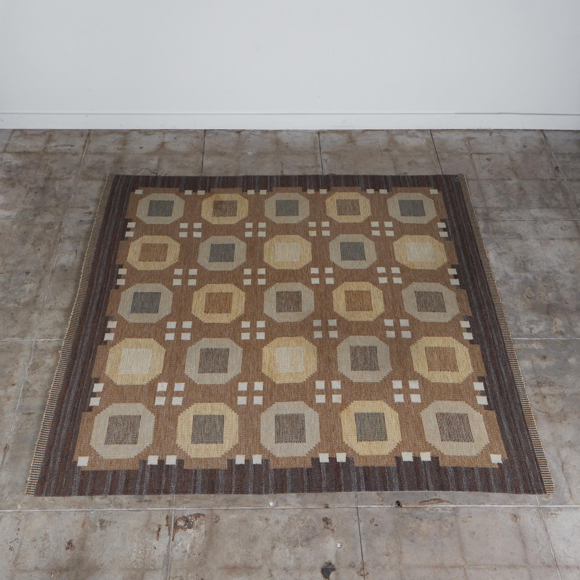 Tapis scandinave de Rakel Callander, circa années 1950, Suède. Comme de nombreux tapis kilim suédois, cette pièce se compose de formes angulaires et de couleurs sourdes. Avec une combinaison de tons terreux chauds et froids, le tapis à tissage plat