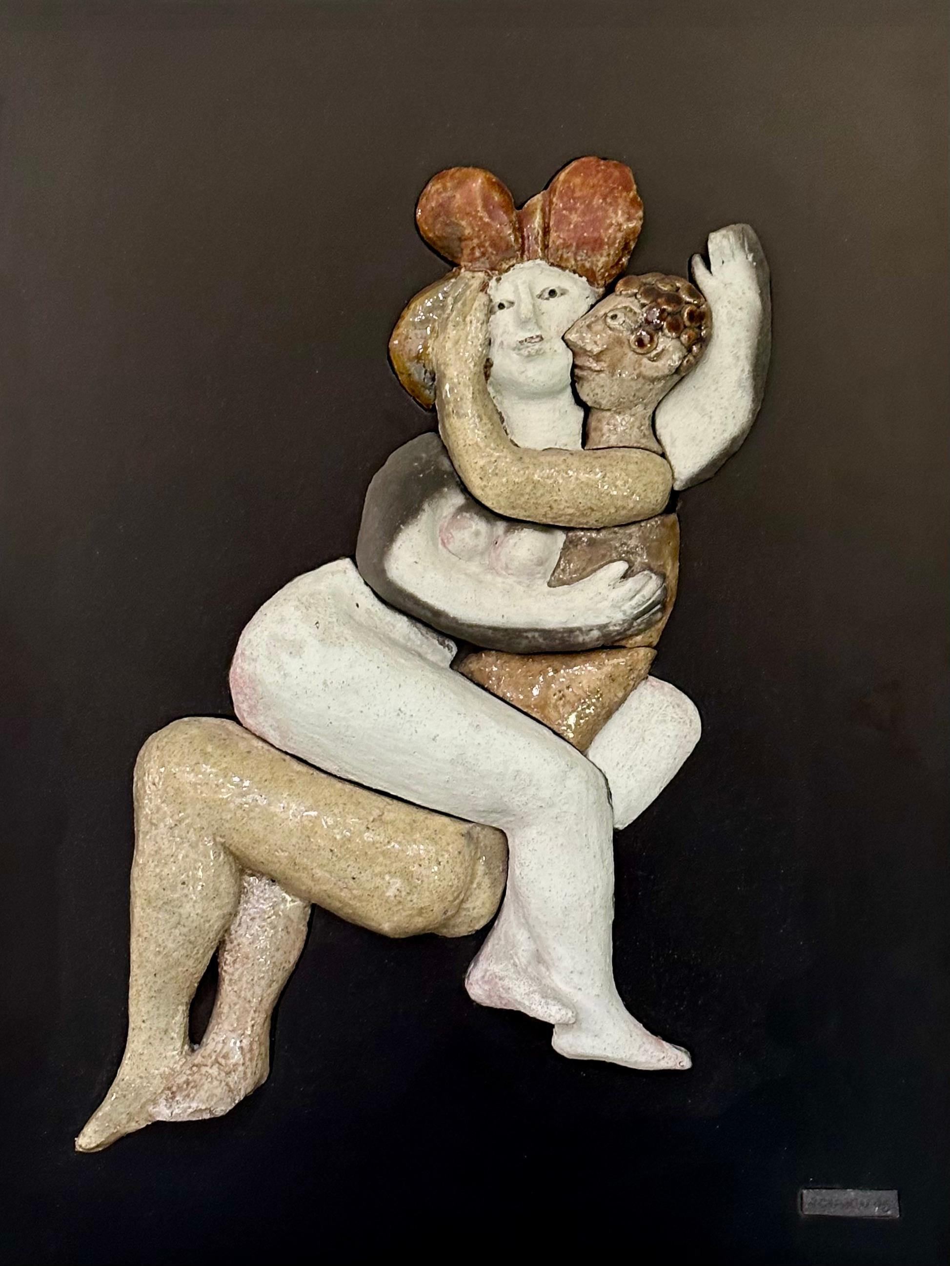 Diese lebendige Szene eines sich umarmenden Paares ist Gemälde und Skulptur zugleich.  ausgeführt in Raku. 
Der schwarz lackierte Holzrahmen wurde vom Künstler selbst angefertigt und verleiht den Figuren eine leicht ausgefallene und humorvolle