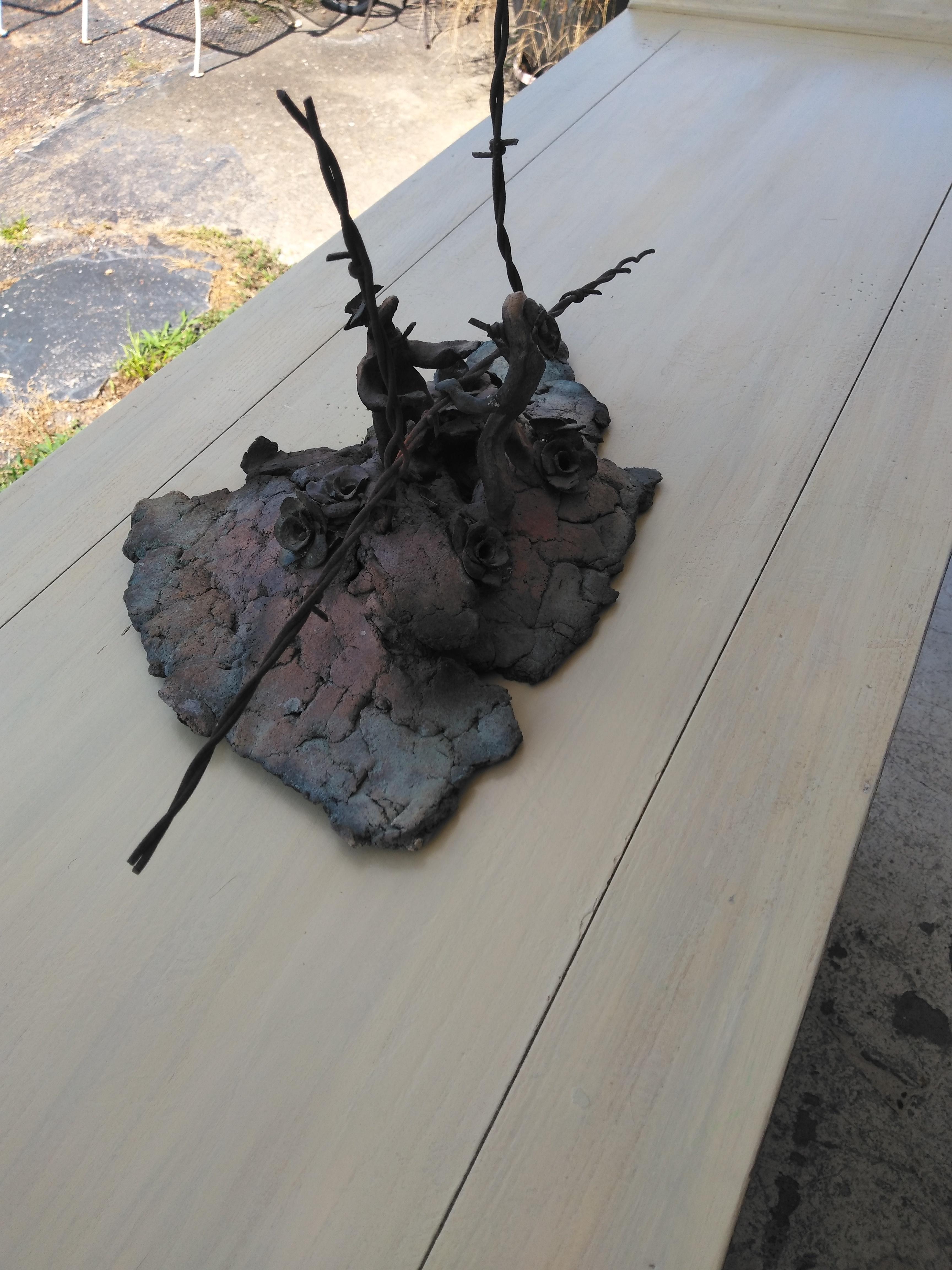 Questa è un'interessante scultura Raku di Bruny Graves. È costruito in argilla con filo spinato e figure. 

Il Raku è una tecnica tradizionale giapponese a bassa cottura che presenta risultati imprevedibili nei suoi smalti.