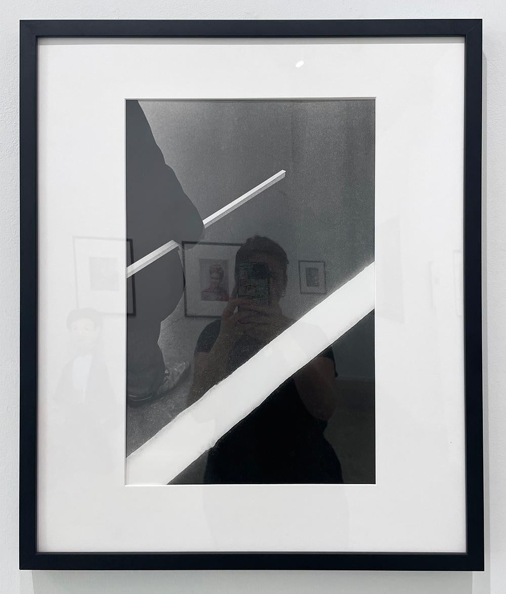 Man, Stick White Stripe de Ralph Gibson est une photographie en noir et blanc d'un homme tenant un bâton blanc, parallèle à une bande blanche peinte sur la chaussée, créant ainsi une image graphique. 

Edition 15/25
Tirage gélatino-argentique
20 x