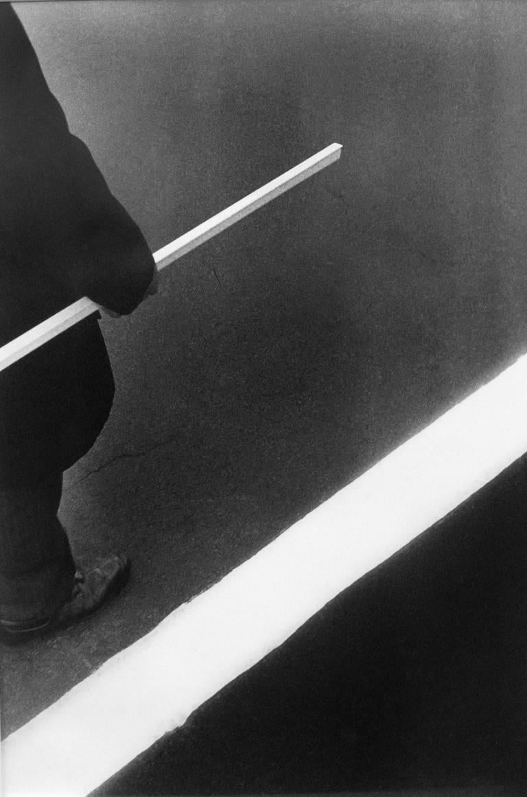 Homme, bâton, bande blanche - Photographie noir et blanc, graphique, minimal