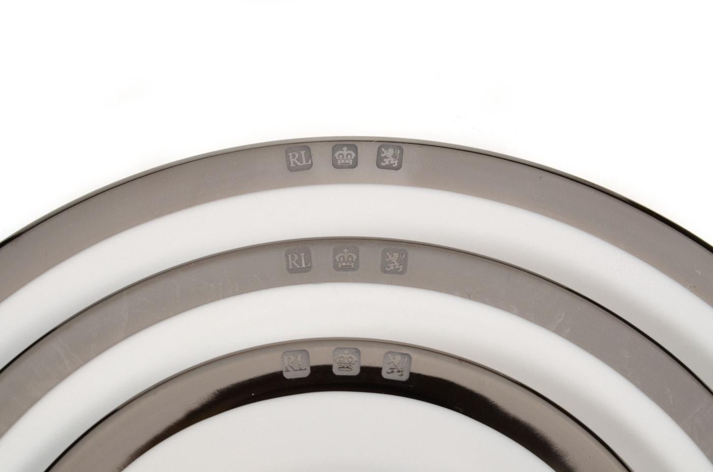 A set of 12 (twelve) place settings in the Academy Platinum pattern by Ralph Lauren Home collection. Bone china. Signed. Imported, production period 1995-2002.

Features a platinum/Silvertone border on white. 

A total of 60 pieces. Each place