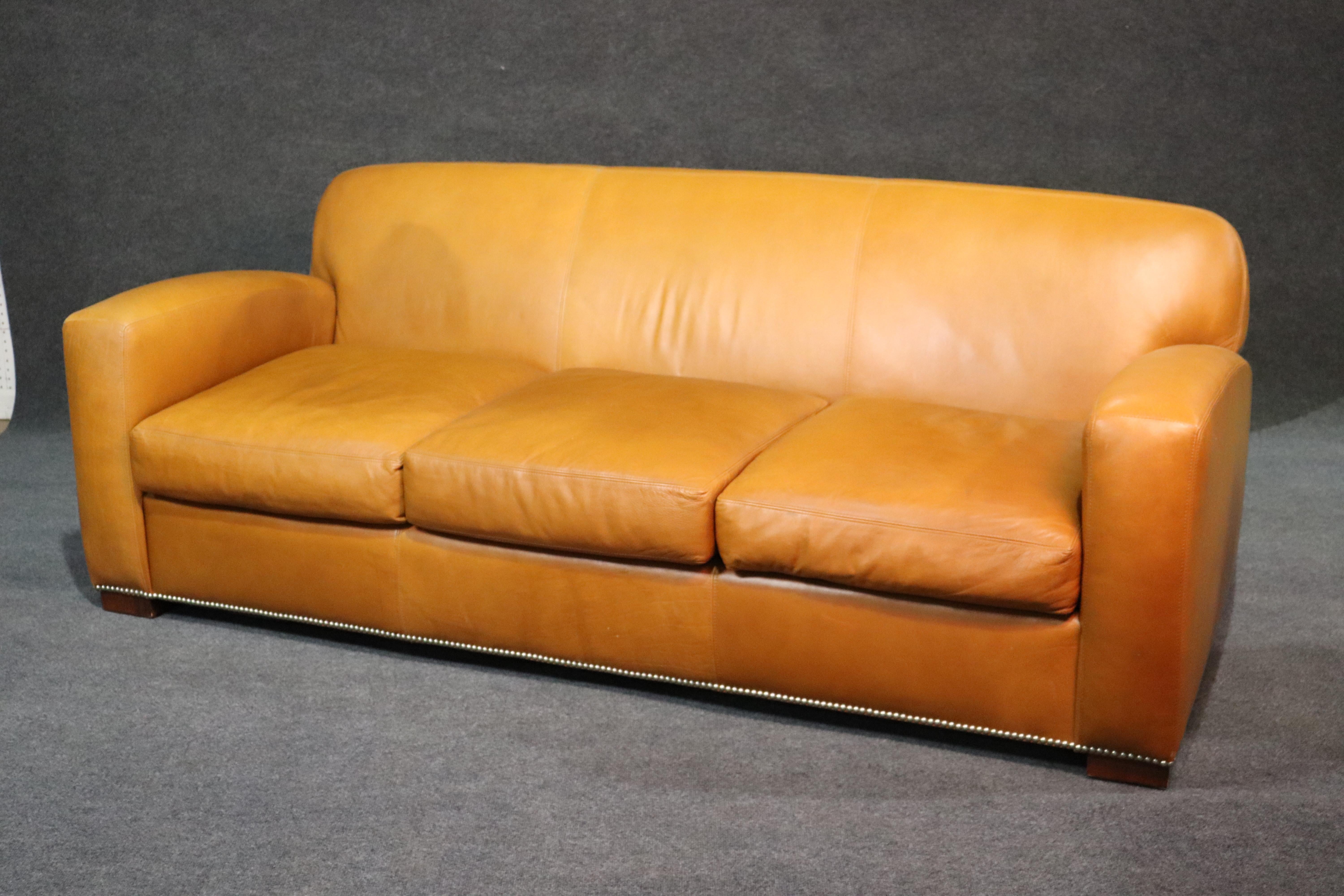 This is an exceptional Ralph Lauren Art deco style sofa. This very large and heavy sofa features beautiful apricot-hued leather and nailhead trim. The leather is in good vintage condition and while it does have some signs of age and use, is still