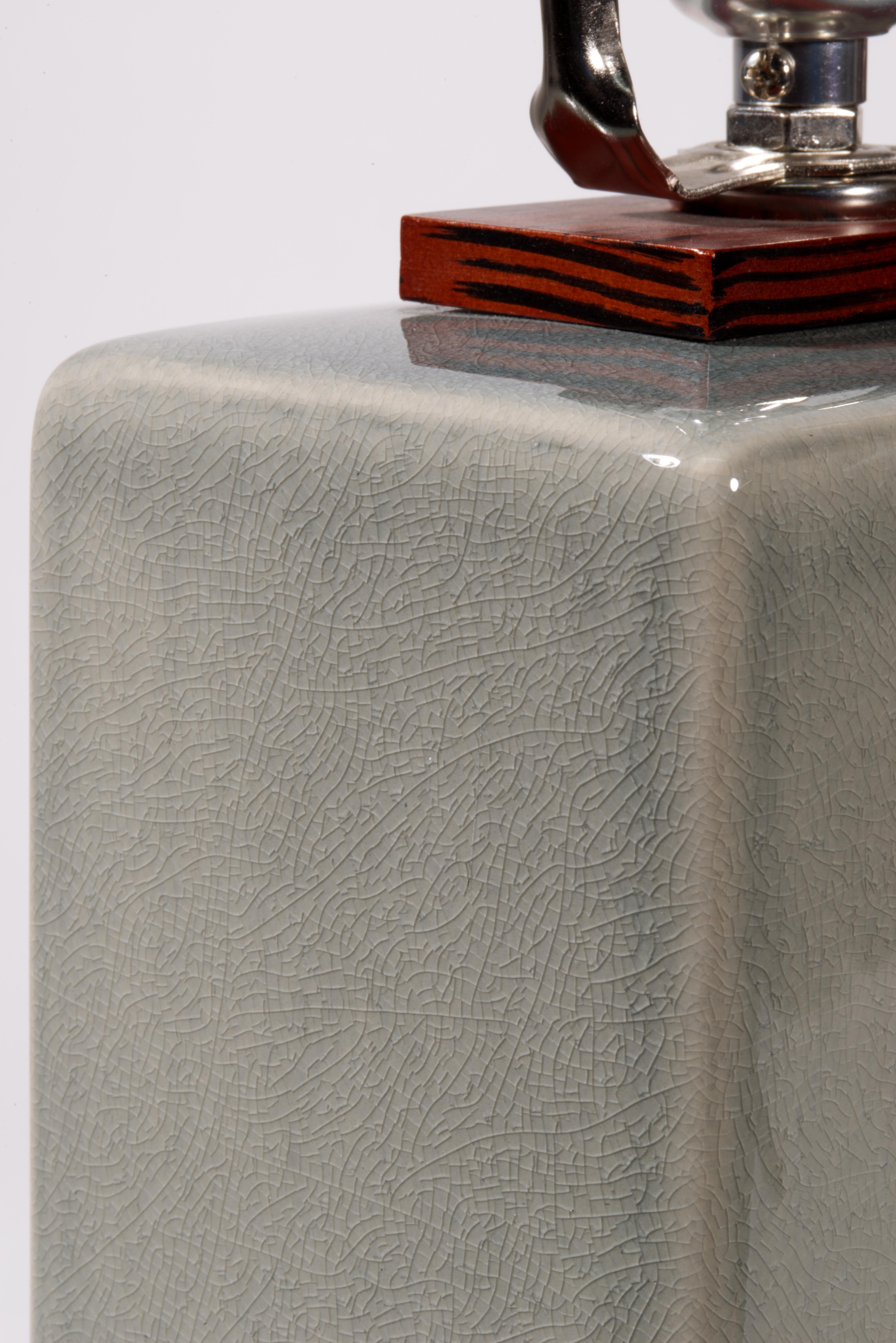  Die elegante Ralph-Lauren-Tischlampe hat einen rechteckigen, skulpturalen Korpus aus Keramik oder Porzellan mit grauer Glasur. Die detailreiche, feine Textur der Craquelé-Glasur wird durch die glänzende, klare Deckglasur hervorgehoben, die der