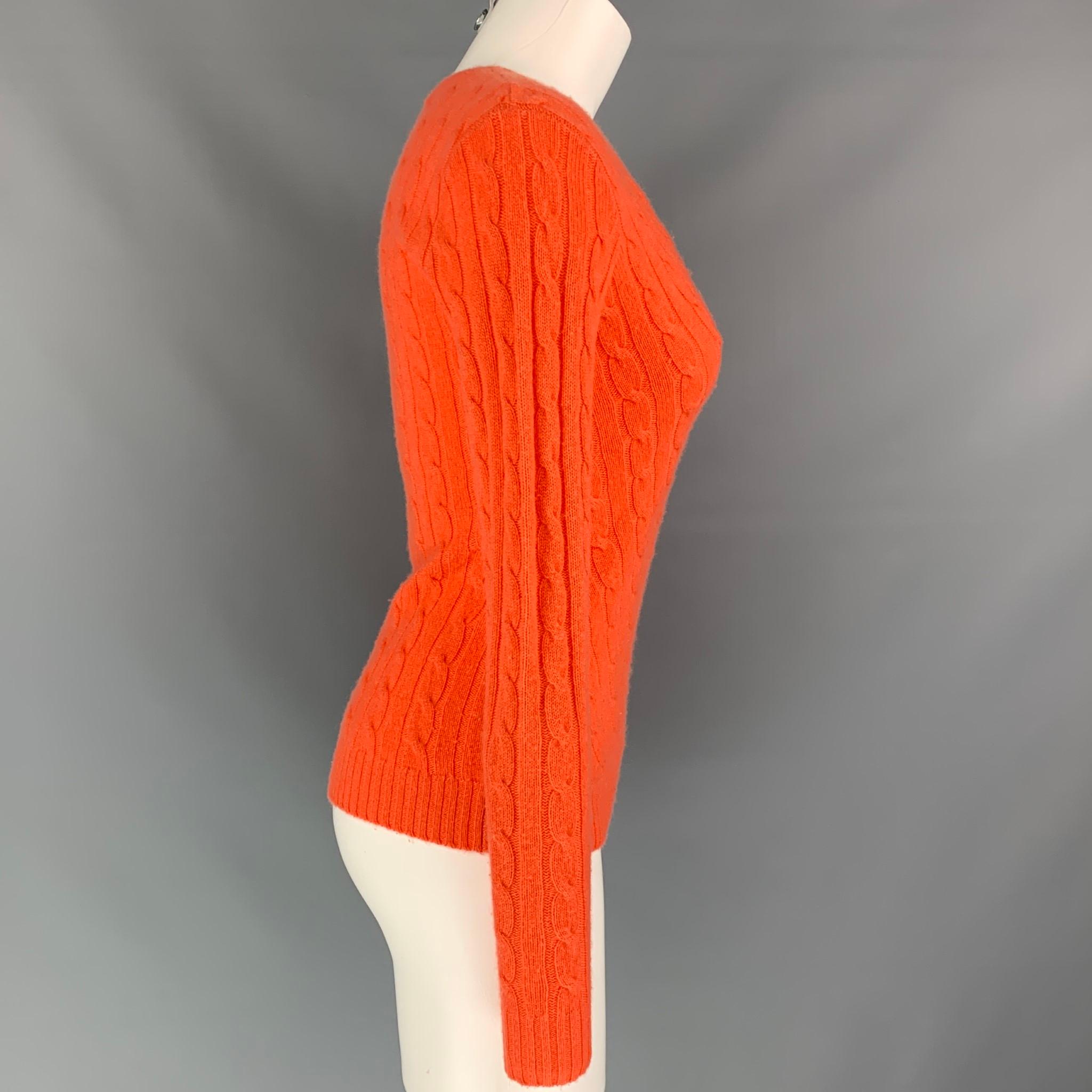 El jersey RALPH LAUREN Black Label se presenta en cachemira de punto por cable naranja, con un corte entallado y cuello de pico. 

Muy buen estado de conservación.
Marcado: S

Medidas:

Hombro: 14,5 pulg.
Busto: 36 pulg.
Manga: 26 pulg.
Longitud: 23