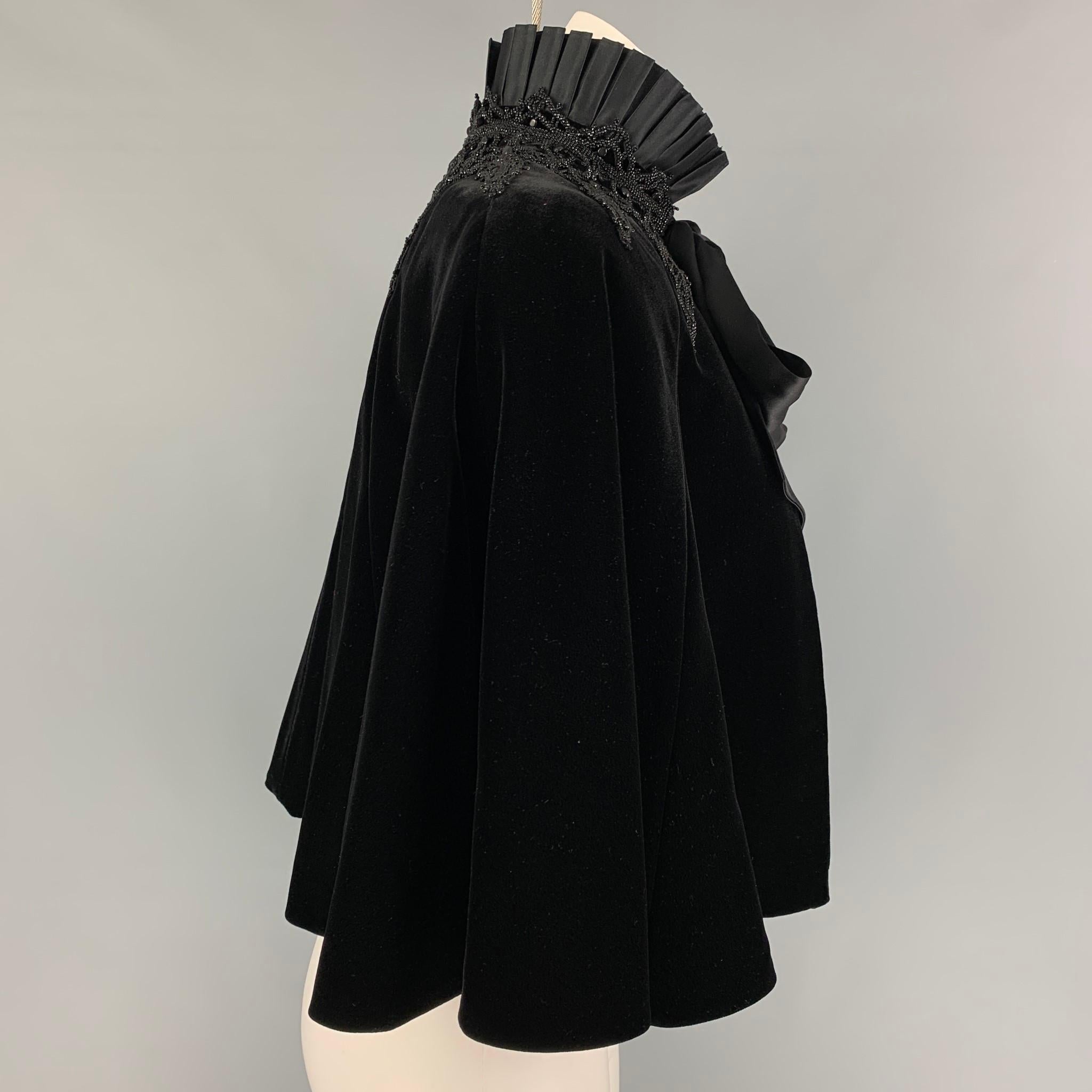 RALPH LAUREN 'Black Label' cape comes in a black velvet viscose with a silk lining featuring a pleated collar, beaded embellishments, and a self tie bow closure. 

Very Good Pre-Owned Condition.
Marked: XS/S
Original Retail Price: