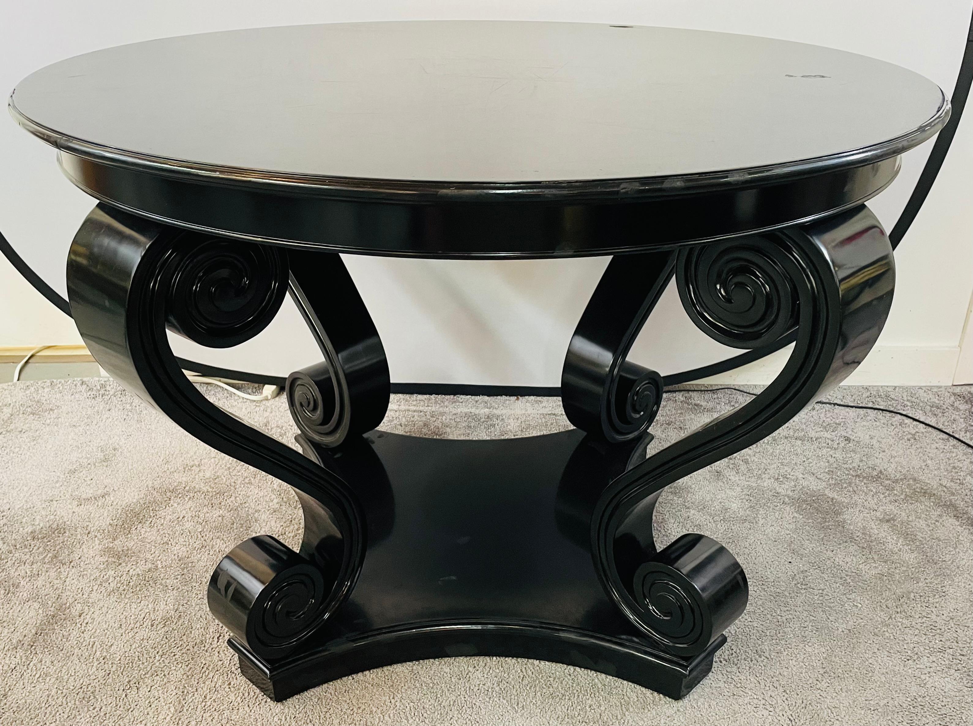 A timeless Ralph Lauren French center hall Mahogany black lacquer table in the style of the Neo Romantic school of 1940's. The round table top is sitting on four stylish and dramatic scroll supports and comes with a custom made glass top.
Glossy